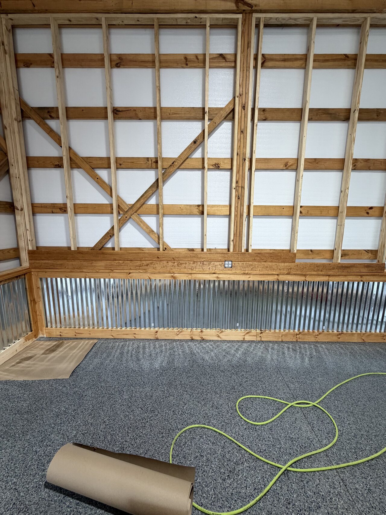 Close view of corrugated metal panels set inside natural wood frames along a finished barn wall.