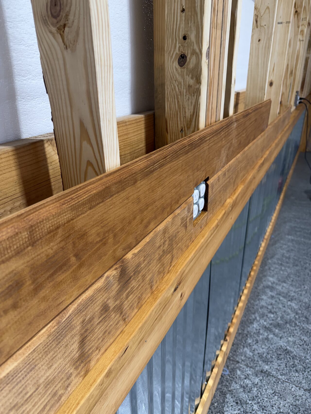 Close view of a stained wood rail with an outlet cut cleanly into the barn wall detail.