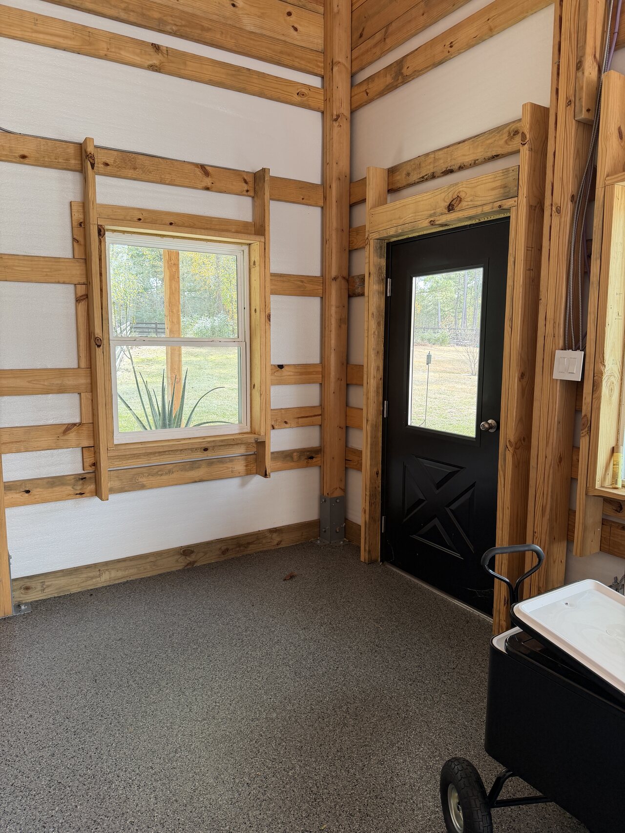 Finished window and door wall with natural wood trim, horizontal rails, and lower wall panels.