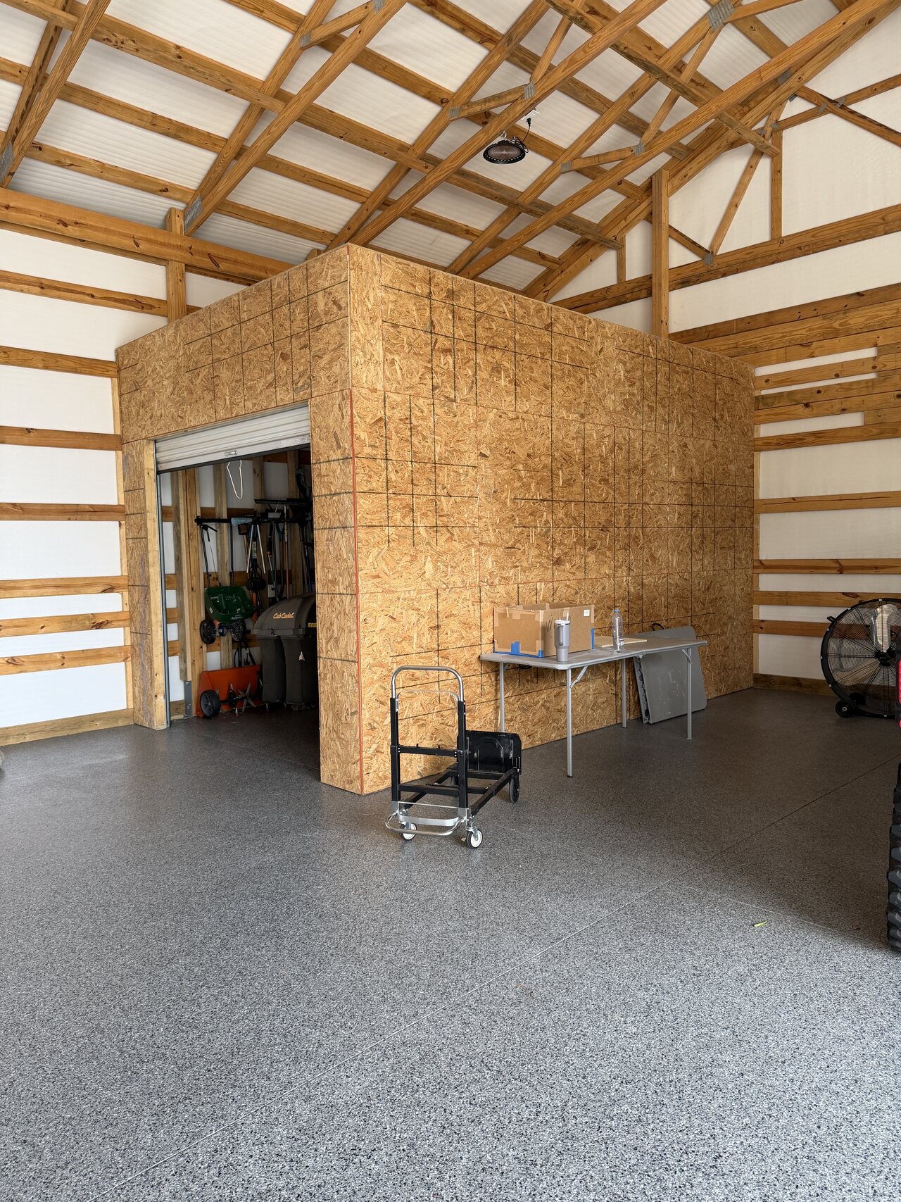 Interior view of the barn utility enclosure wrapped with OSB panels beneath exposed wood trusses.