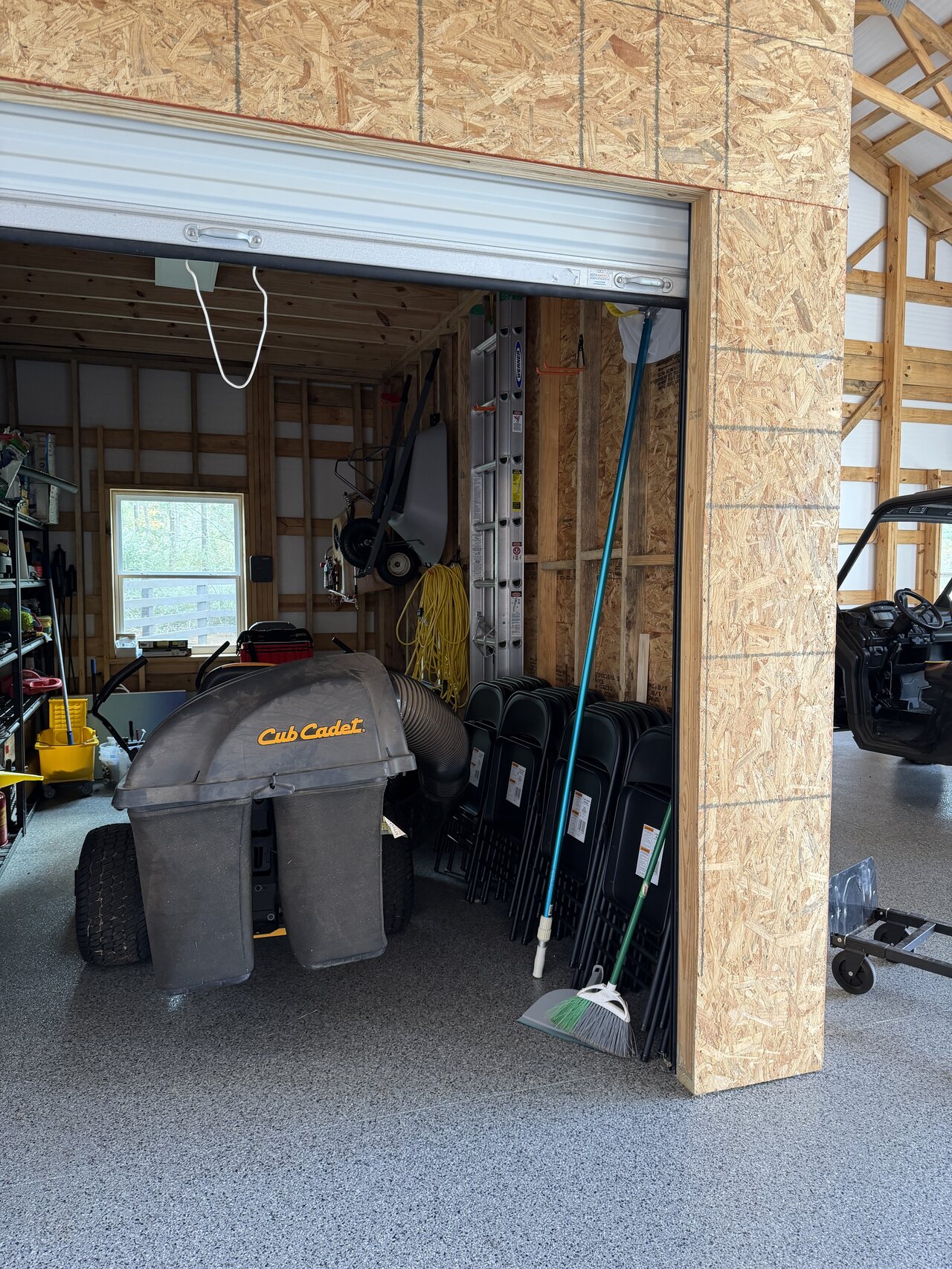 Roll-up opening in a barn utility enclosure framed with OSB panels and natural wood trim.