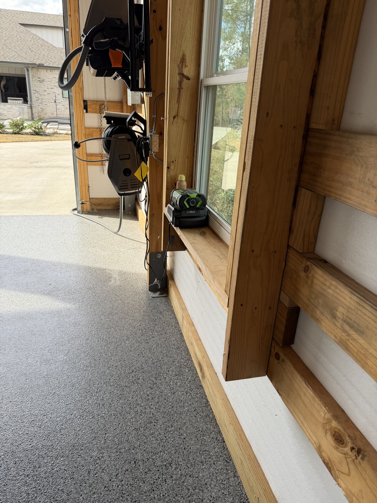 Door-side lower wall detail with natural wood trim, post, base rail, and concrete floor.