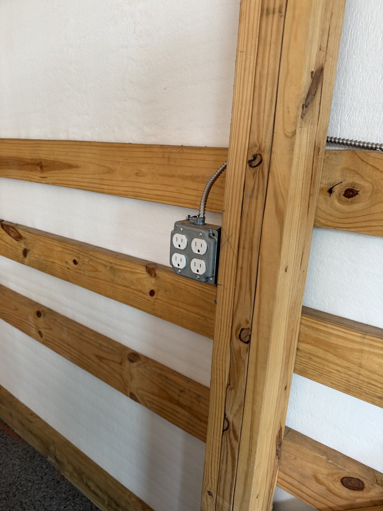 Electrical box integrated into a barn wall with natural wood posts and horizontal rails.