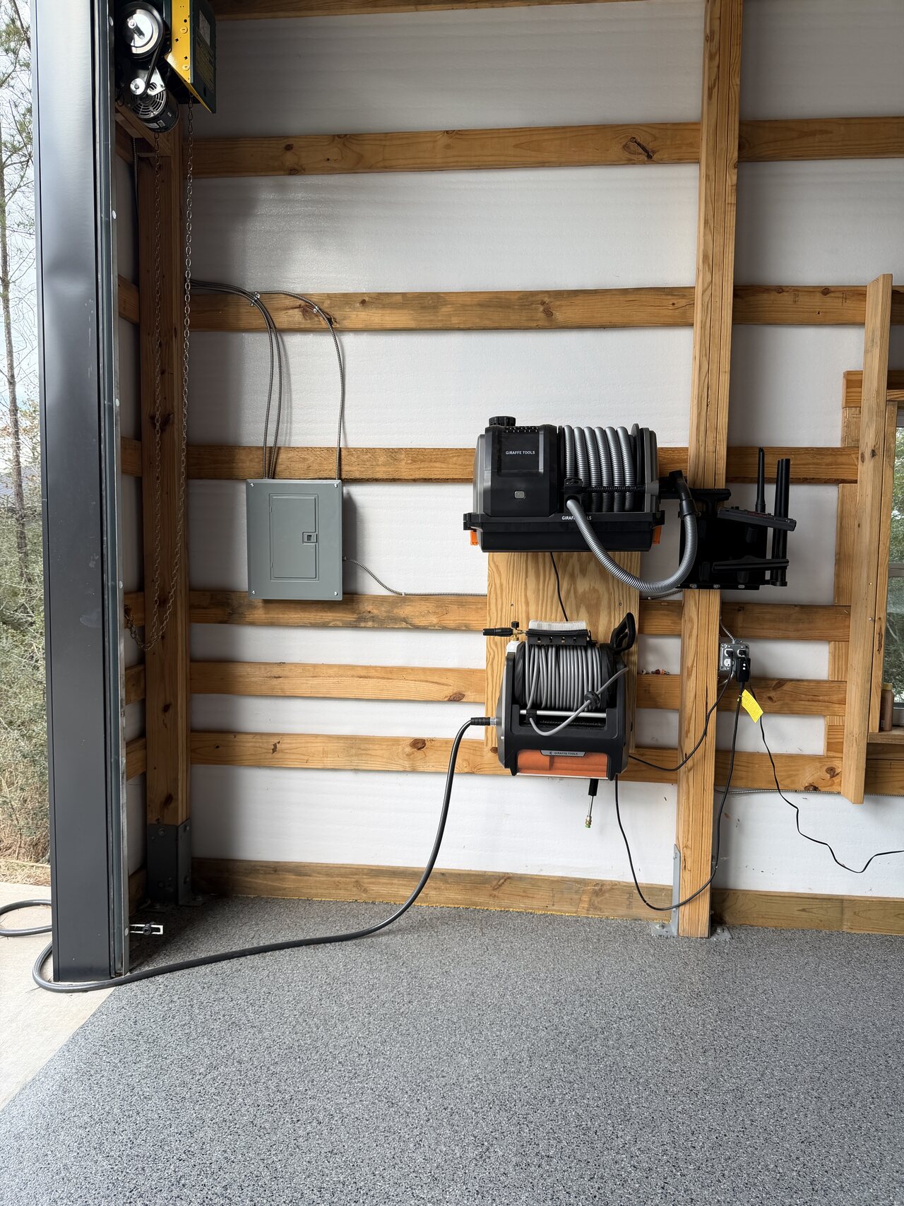 Wall-mounted reels and equipment against a finished barn wall with natural wood rails.