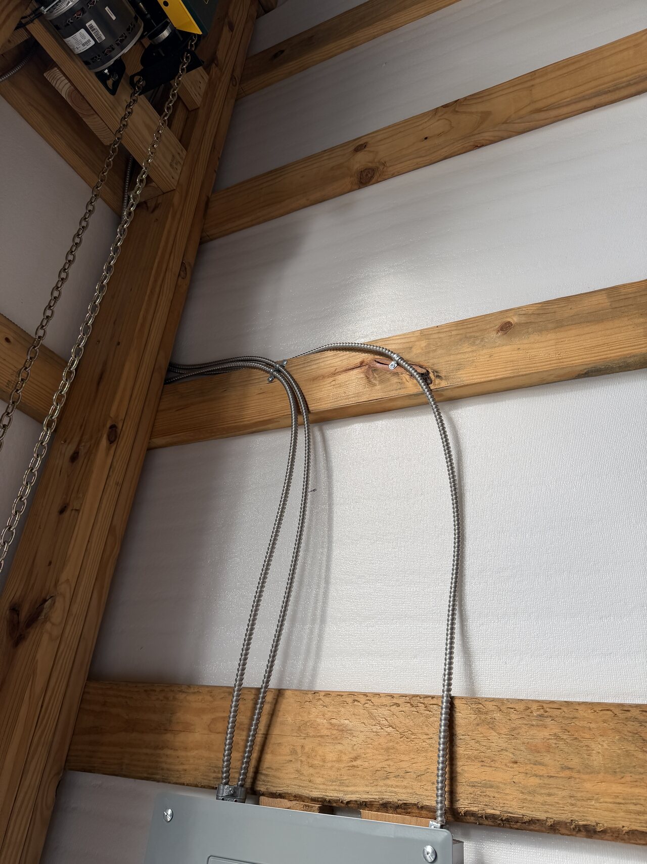 Conduit drop routed through exposed natural wood wall framing in the barn interior.