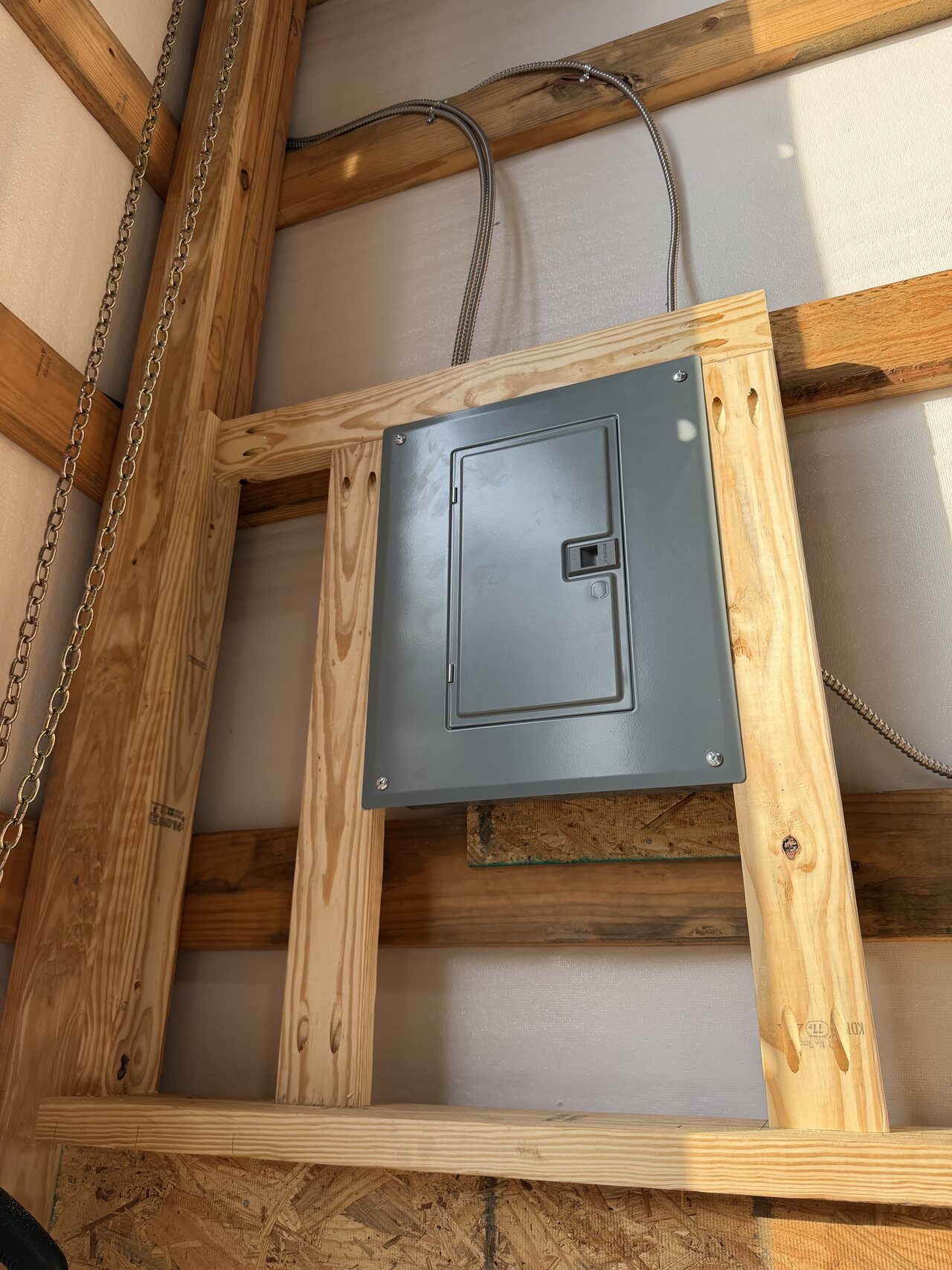 Electrical panel area boxed with natural wood framing for access and finish coordination.