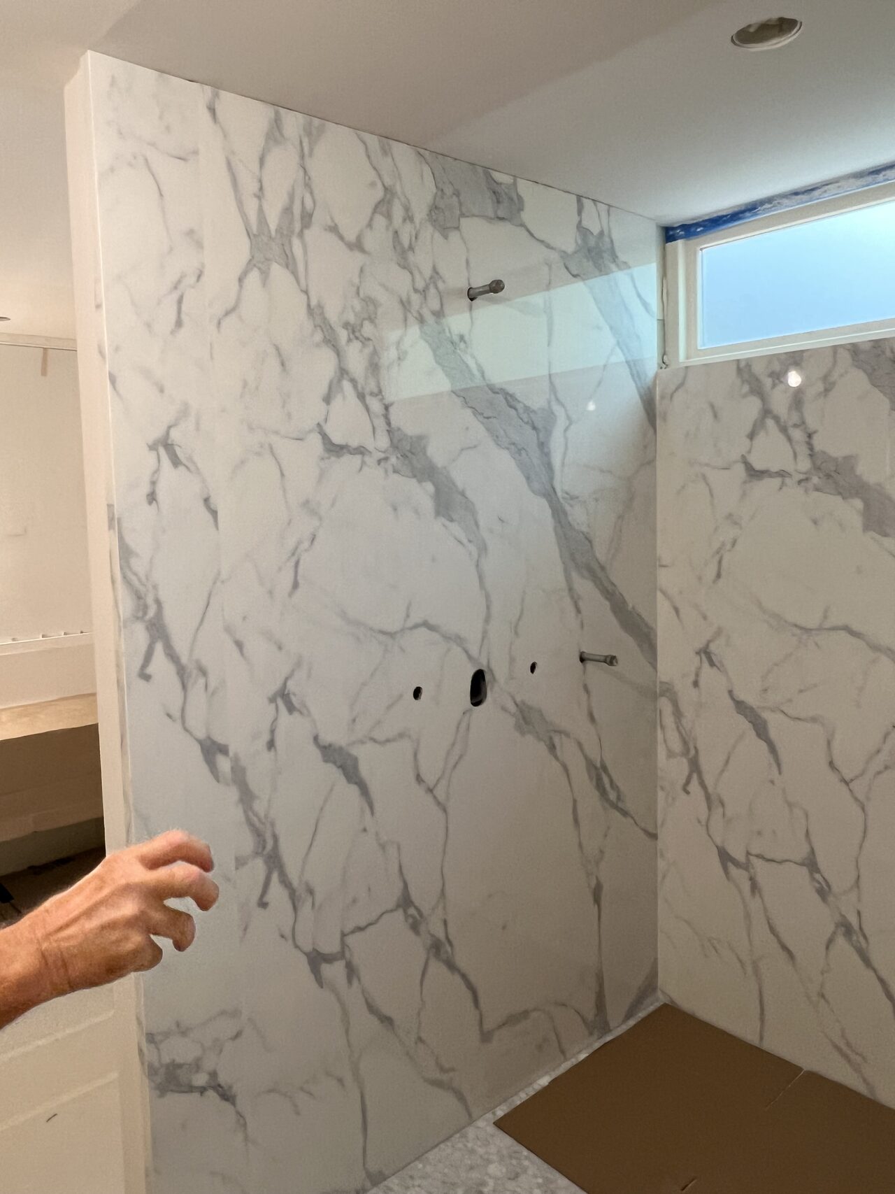 Large-format shower wall panels inspected for slab layout, veining direction, and wall-to-tub finish coordination for a Joel Hodge project.