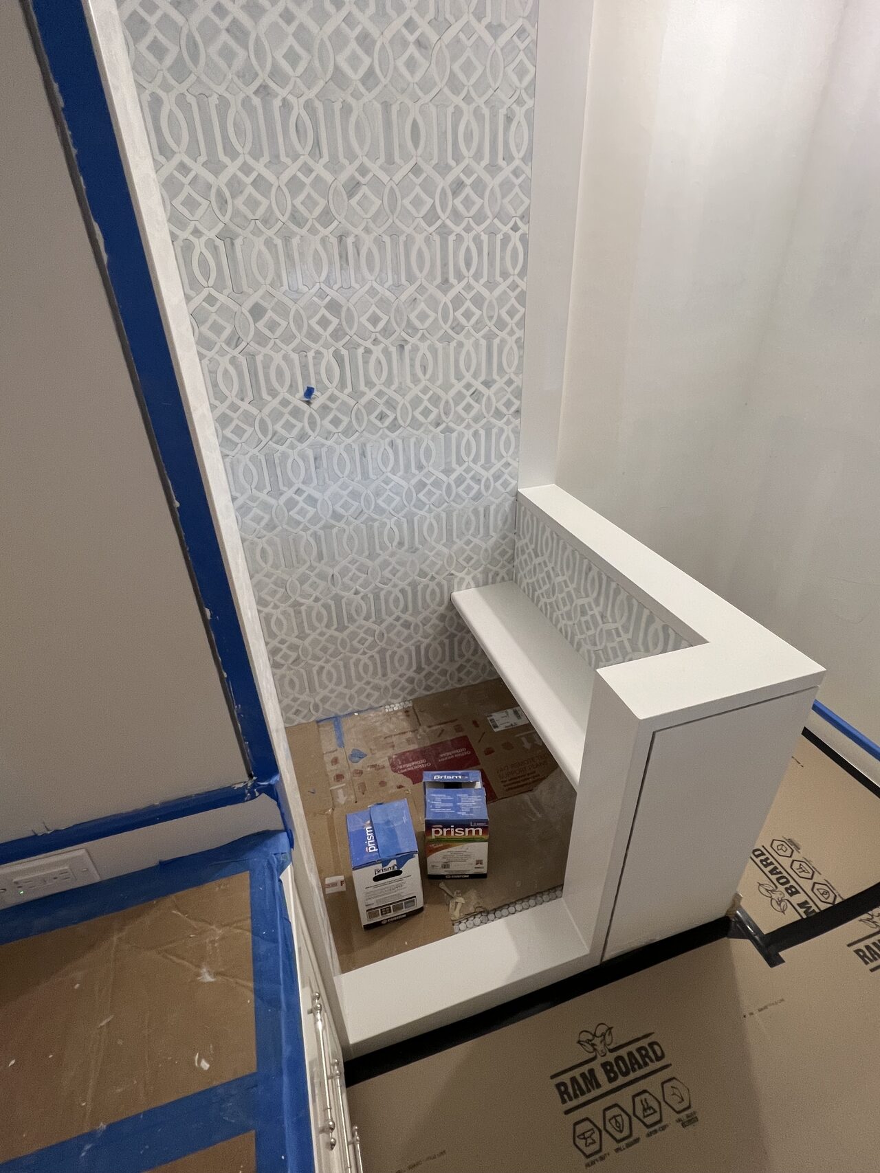 Protected shower opening with taped edges while tile and trim details were being reviewed around the wet area for a Joel Hodge project.