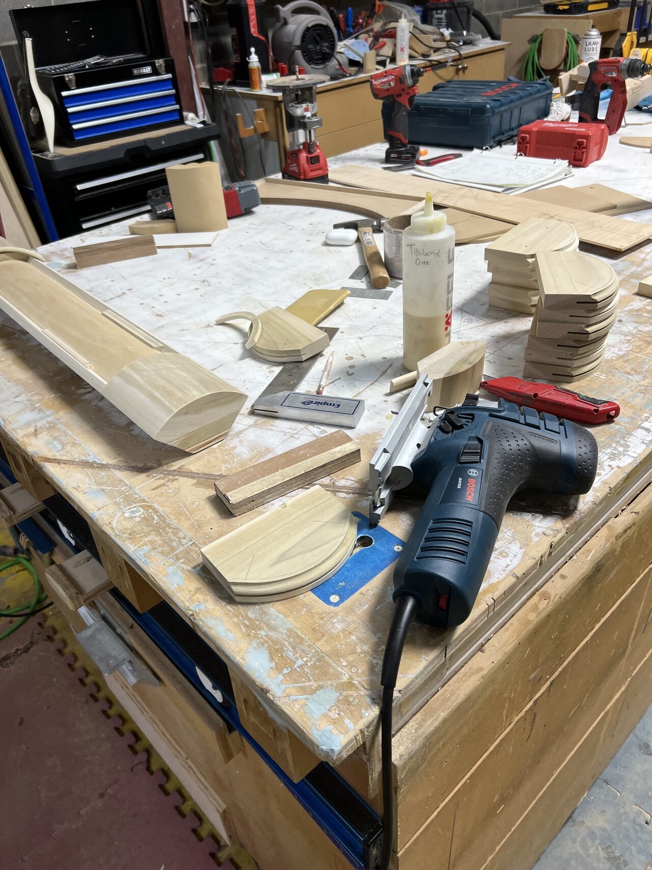 Templates, blocking, and stacked parts organized on the shop bench for repeatable radius fabrication for a Joel Hodge project.