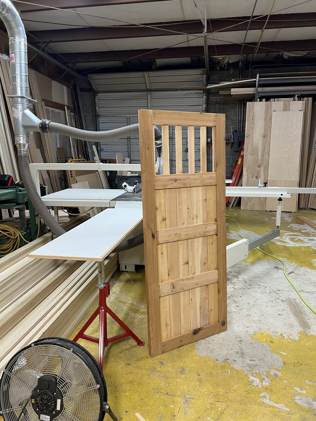 Finished custom wood gate standing in the shop after assembly and before site installation for a Joel Hodge project.