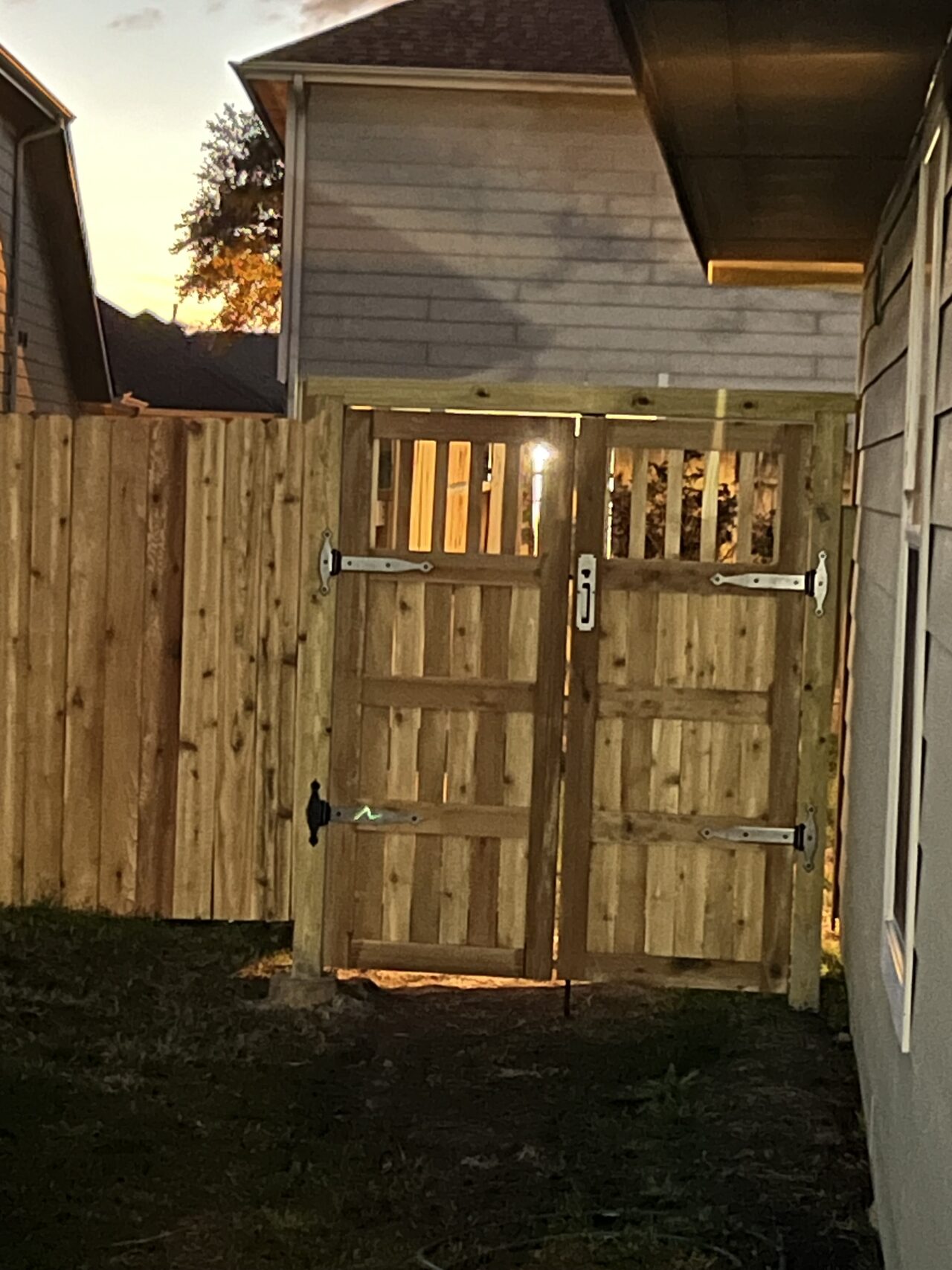 Installed gate viewed after dark to confirm fit, panel appearance, and exterior access clearance for a Joel Hodge project.