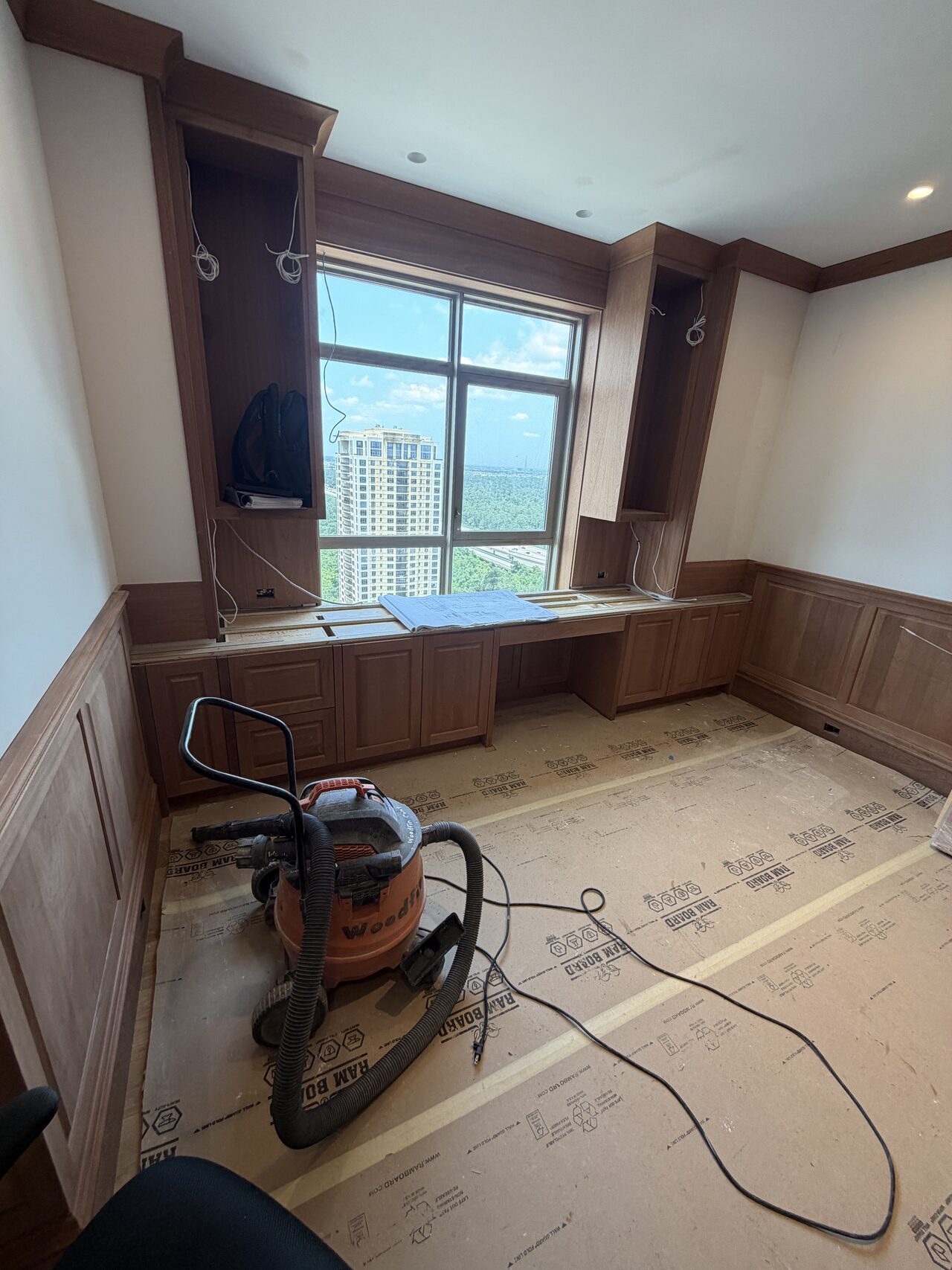 Stained wood library cabinetry spanning the window wall with shelves, drawers, and finished face frames aligned for a Joel Hodge project.