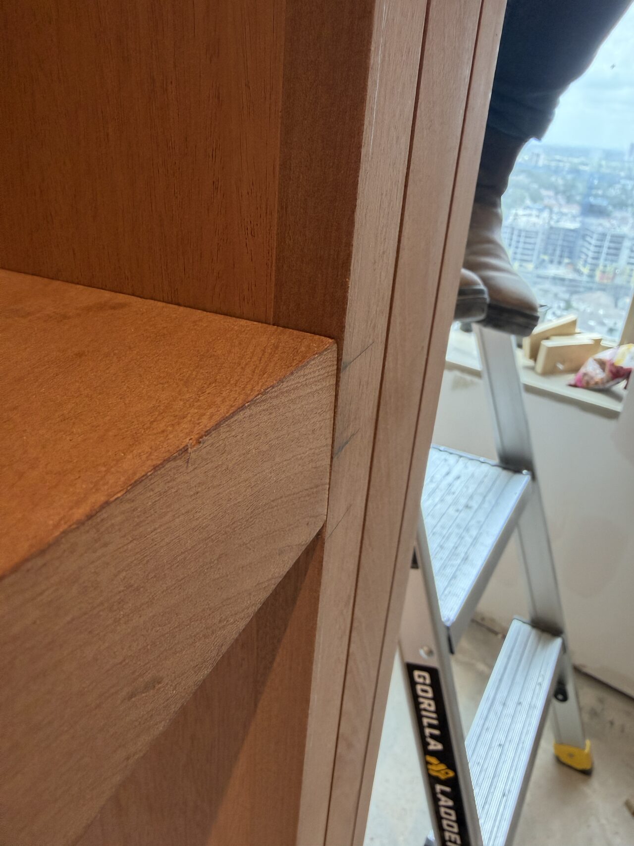 Shelf edge and vertical stile alignment checked where the cabinet run meets the window wall for a Joel Hodge project.