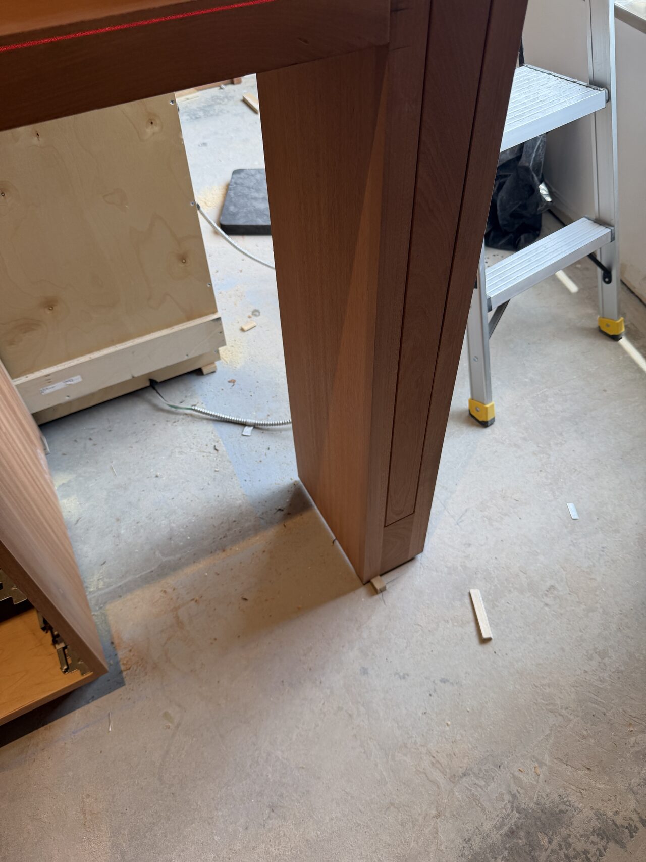 Tall side panel and cabinet leg reviewed at the floor for plumb fit and clean base transition for a Joel Hodge project.