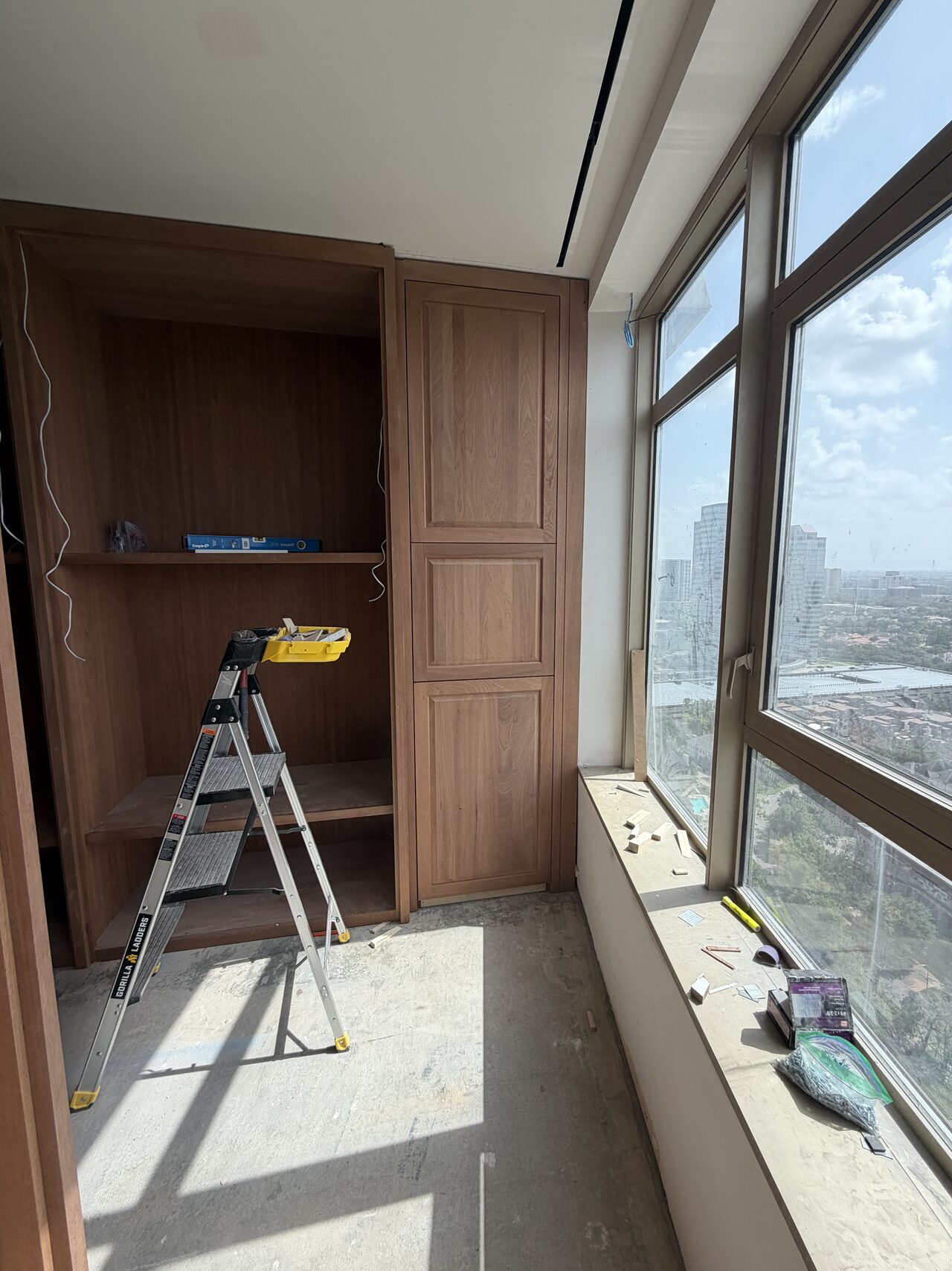Window-wall built-in with ladder and tools in place during final cabinet fitting and trim work for a Joel Hodge project.