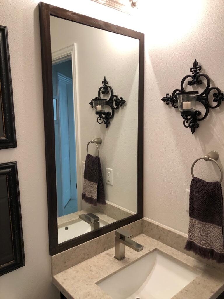 Dark-framed mirror, towel hardware, and wall sconce placement reviewed above the bathroom vanity for a Joel Hodge project.