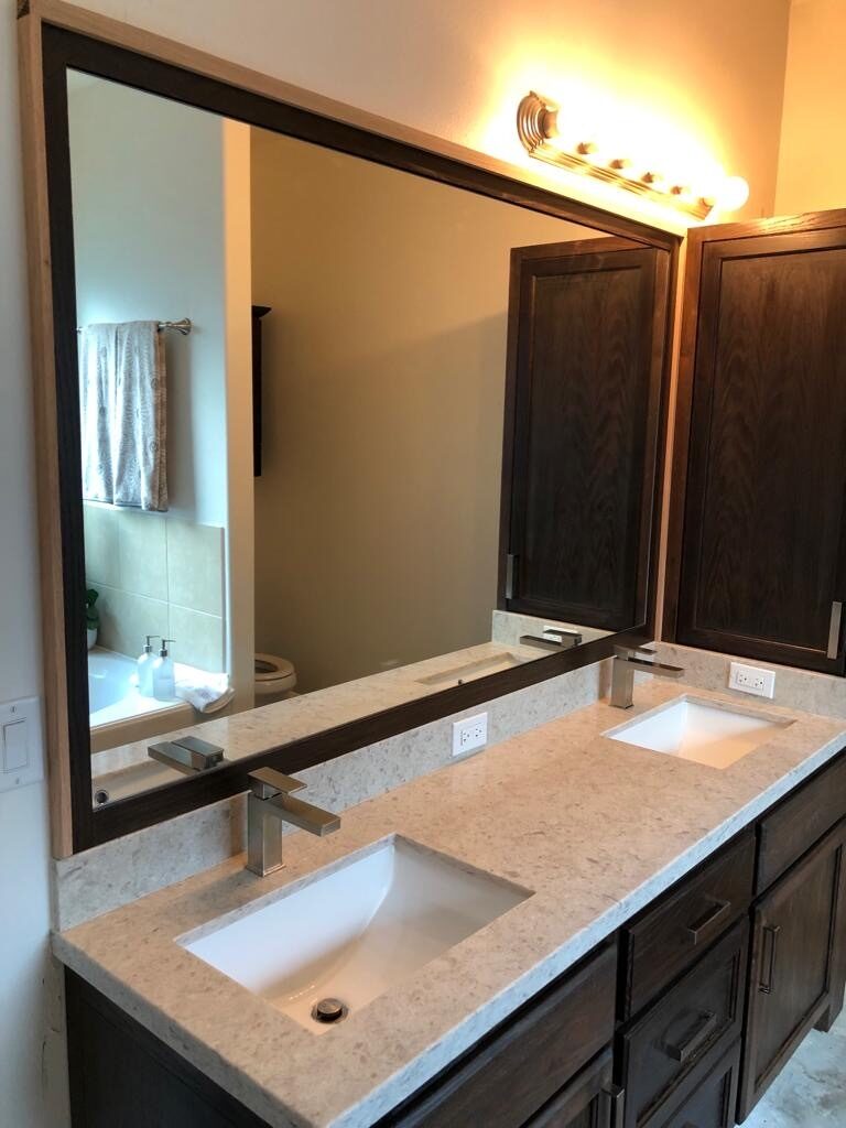 Dark double vanity and wide mirror checked for sink spacing, counter line, and light fixture alignment for a Joel Hodge project.