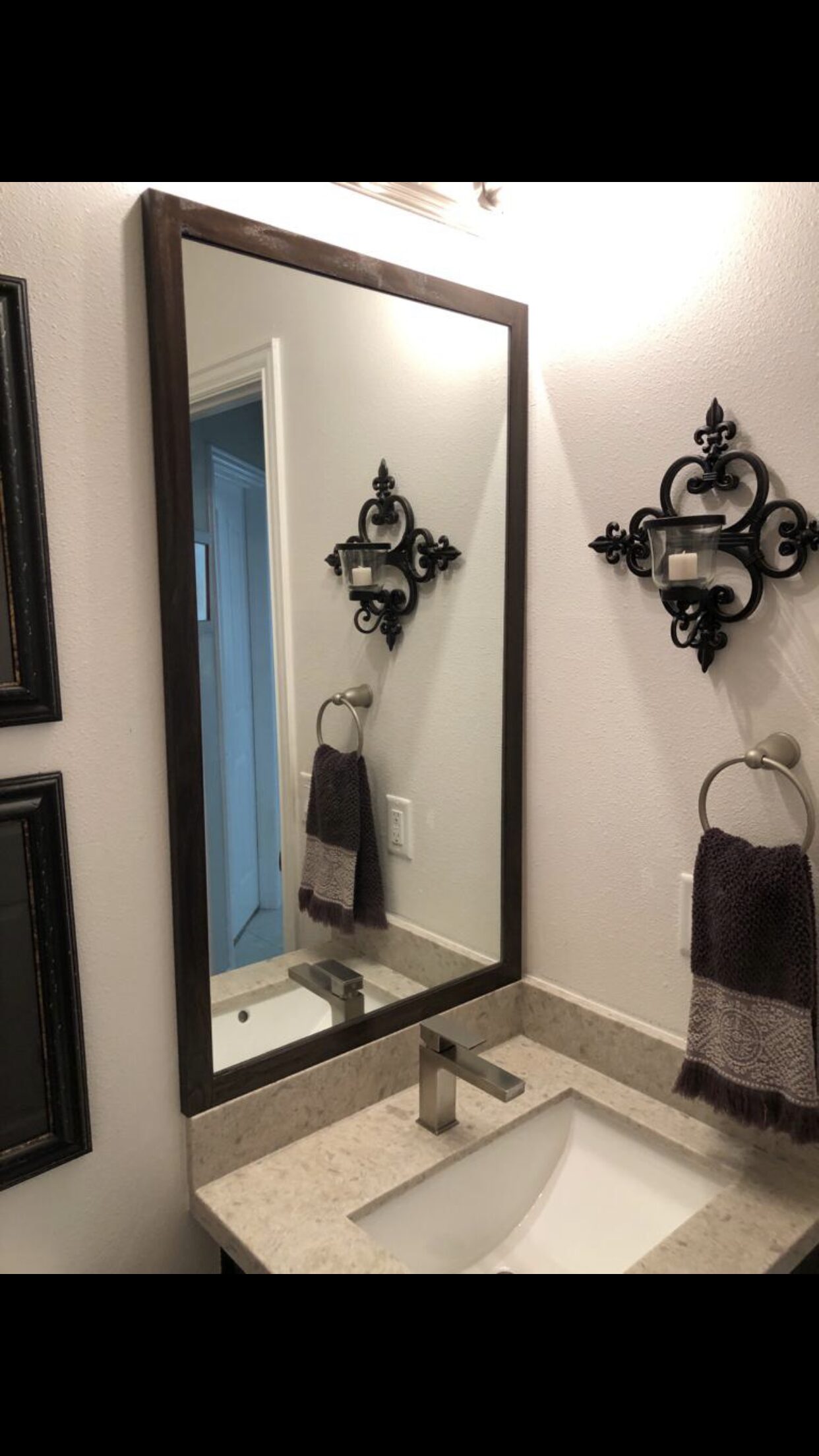 Vertical view of the vanity wall with mirror, sink, towel ring, and nearby trim transition for a Joel Hodge project.