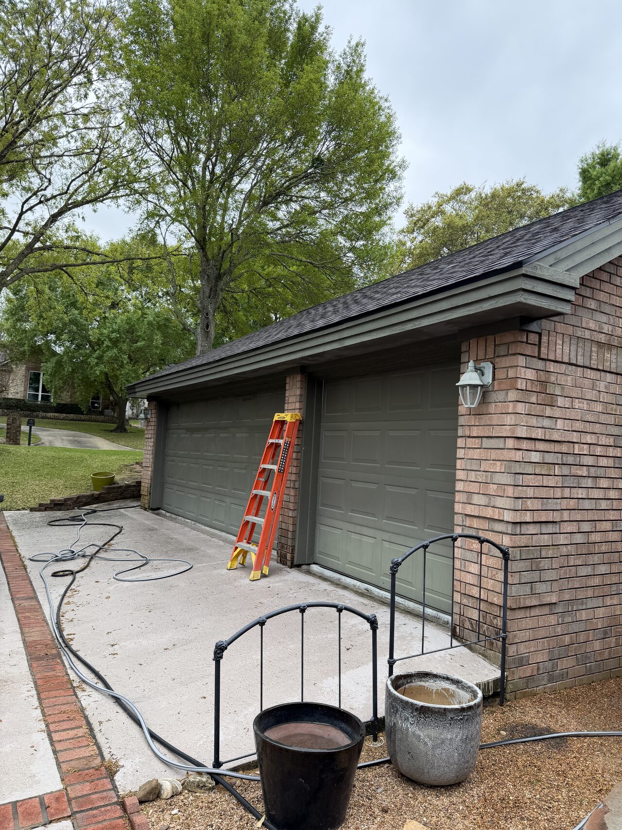 Driveway and side roofline access reviewed with ladder placement before exterior trim assessment for a Joel Hodge project.