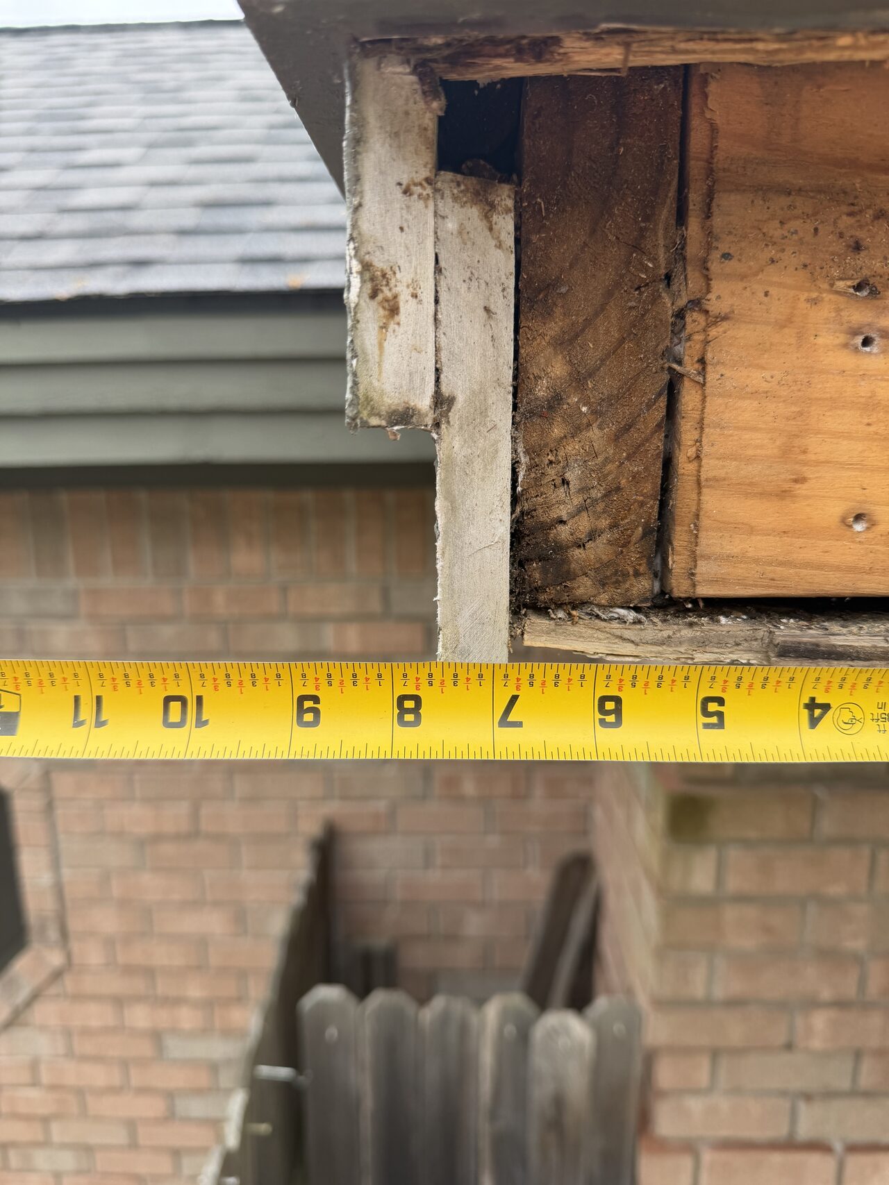 Tape measurement at the eave and fascia area used to confirm trim dimensions in the field for a Joel Hodge project.
