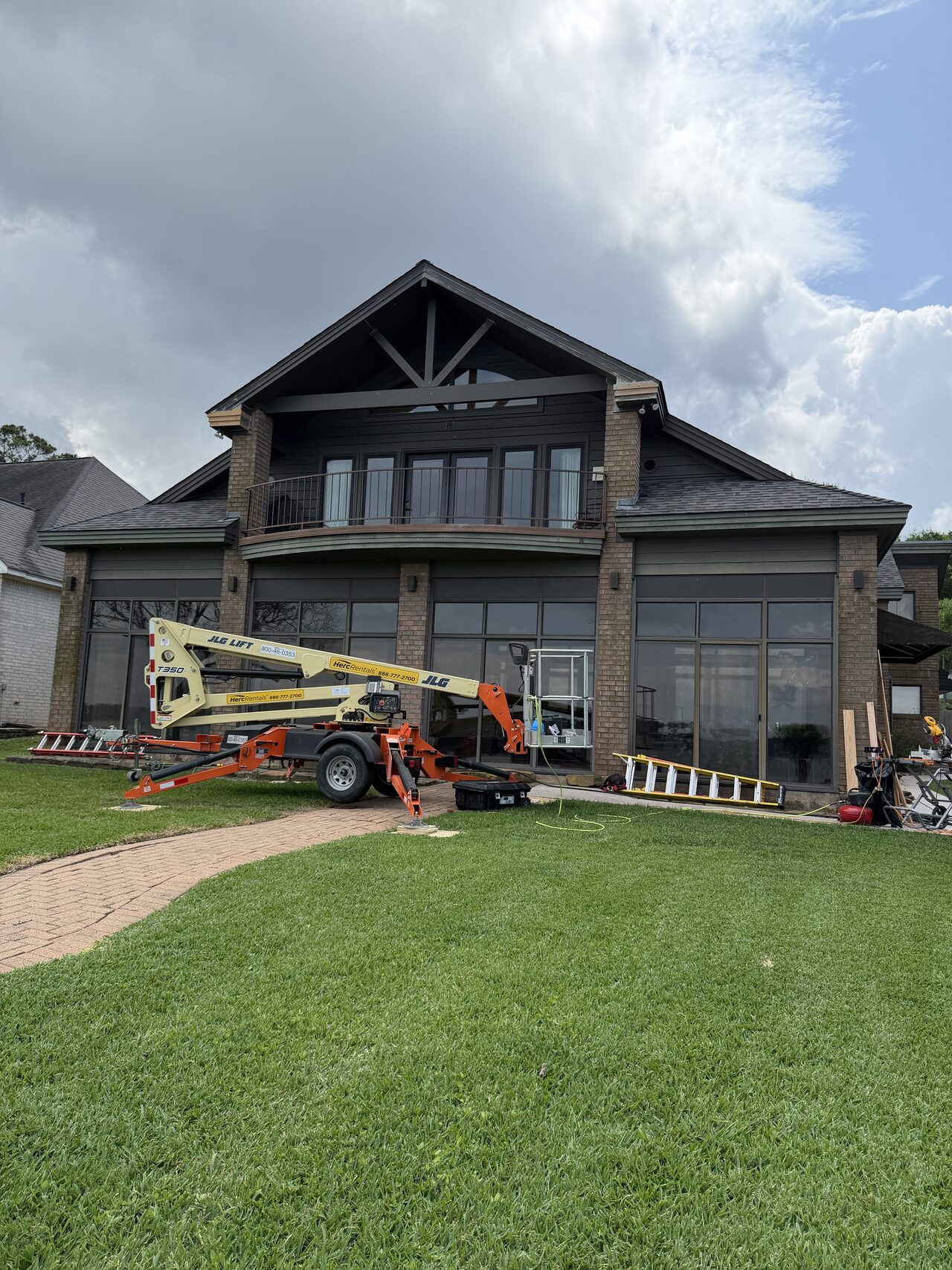 Lift positioned at the front elevation to reach upper gable, roof, and window trim areas for a Joel Hodge project.