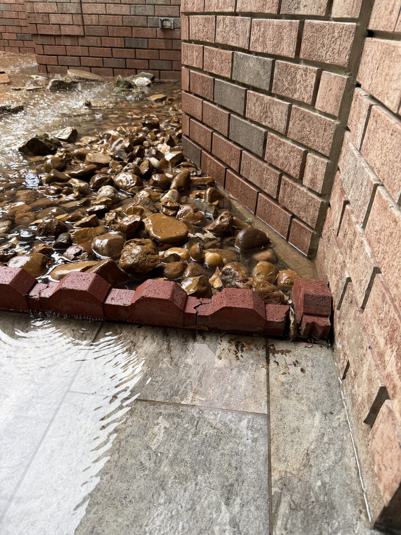 Debris and drainage condition along the brick foundation documented during exterior assessment for a Joel Hodge project.