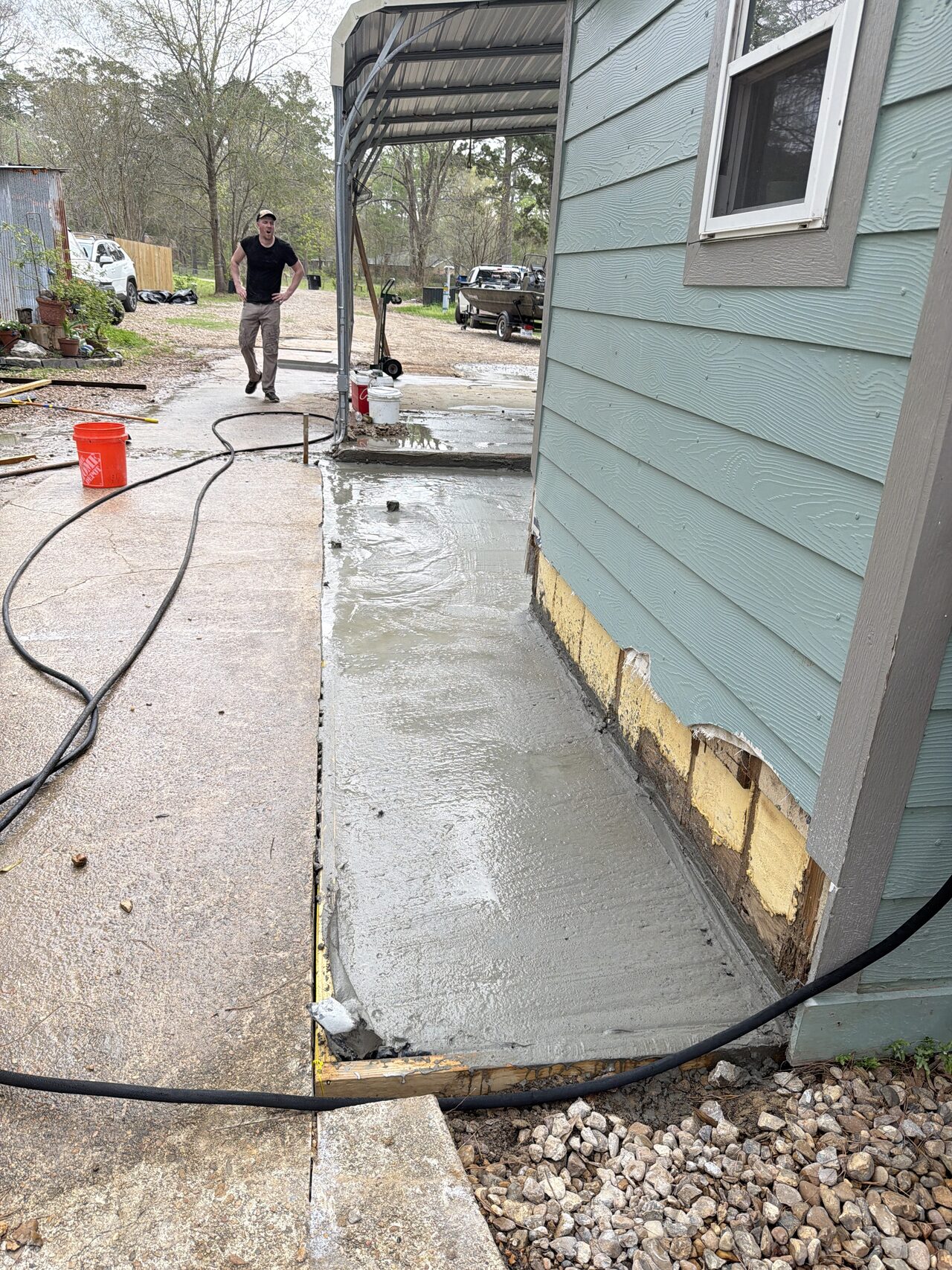 Exterior concrete and siding base condition reviewed along the side wall before trim and opening work for a Joel Hodge project.