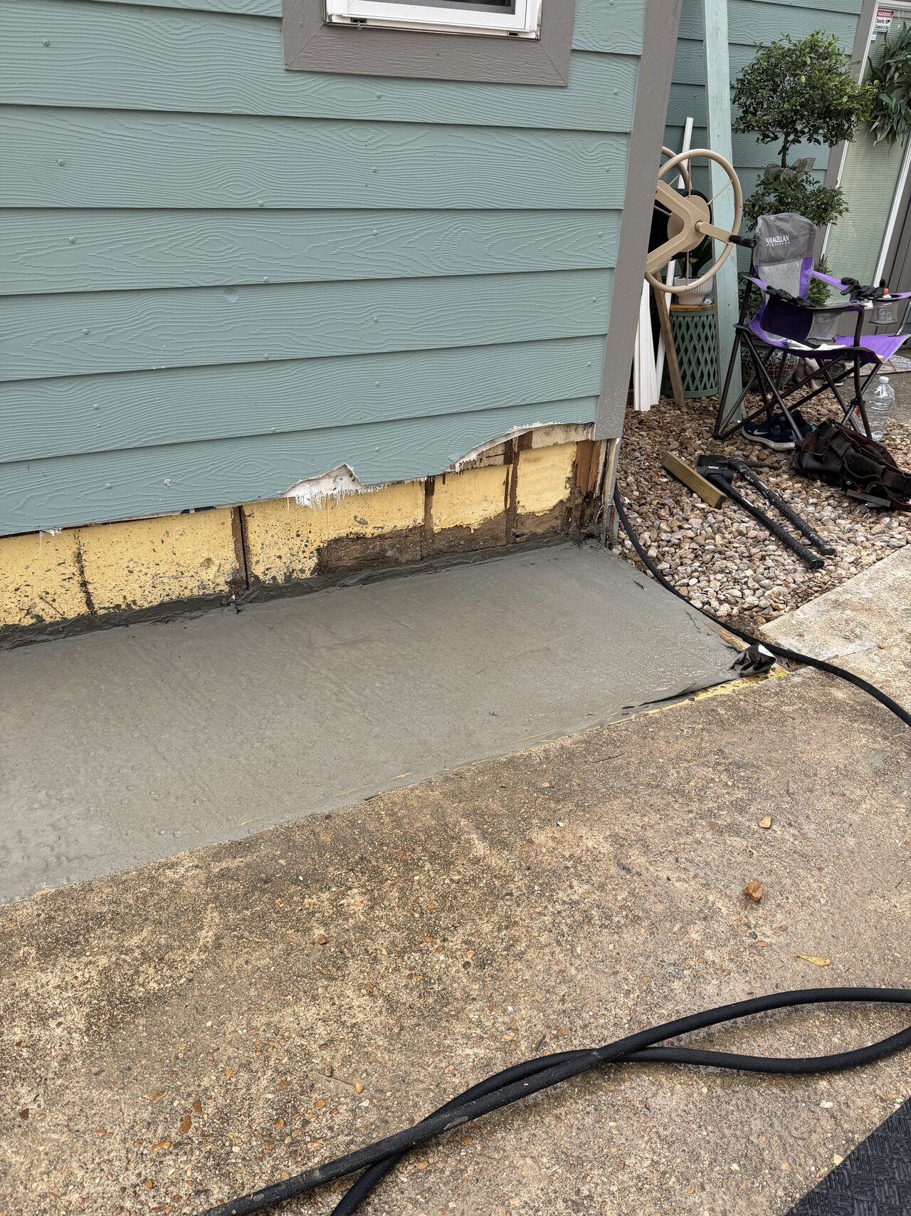 Ground line and siding edge checked near the hose bib for moisture, clearance, and finish transition concerns for a Joel Hodge project.