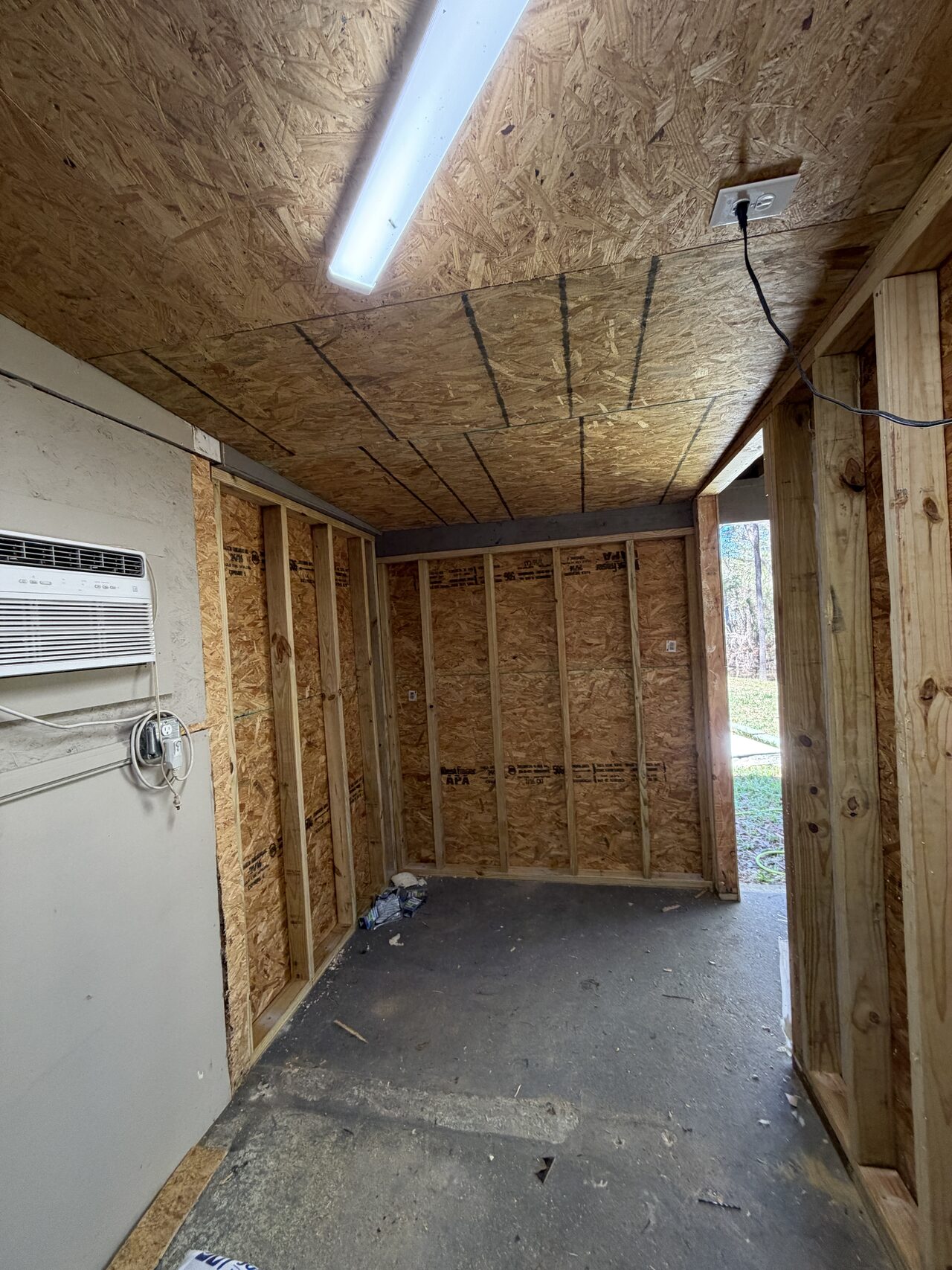 Second interior room angle showing ceiling framing, wall sheathing, and work light setup for a Joel Hodge project.