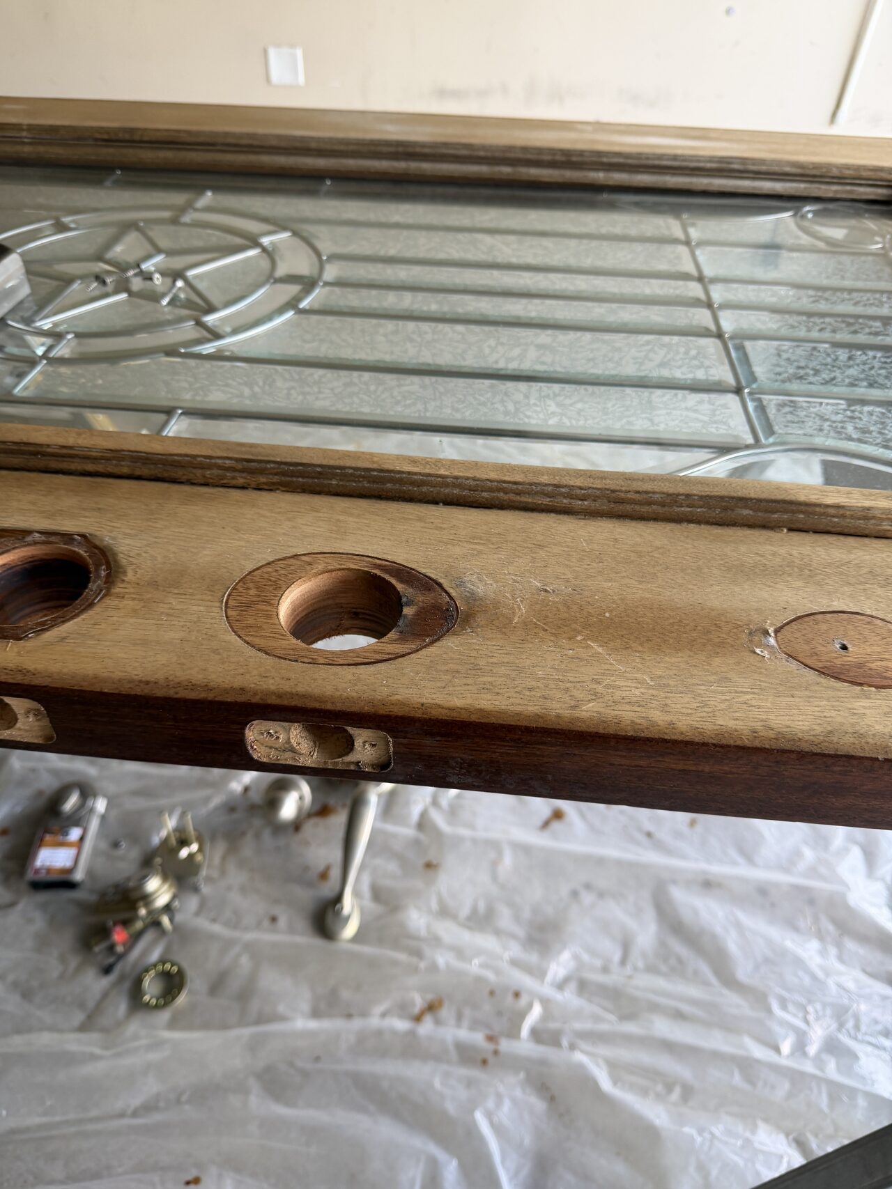 Entry door slab on supports with hardware bore areas exposed during refinishing preparation for a Joel Hodge project.