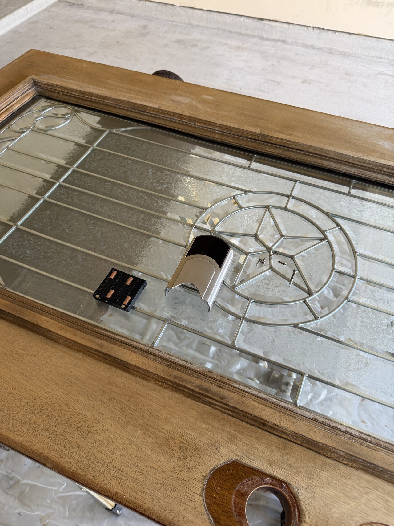 Glass entry door close-up showing lockset cutout, stained rail, and finish condition review for a Joel Hodge project.