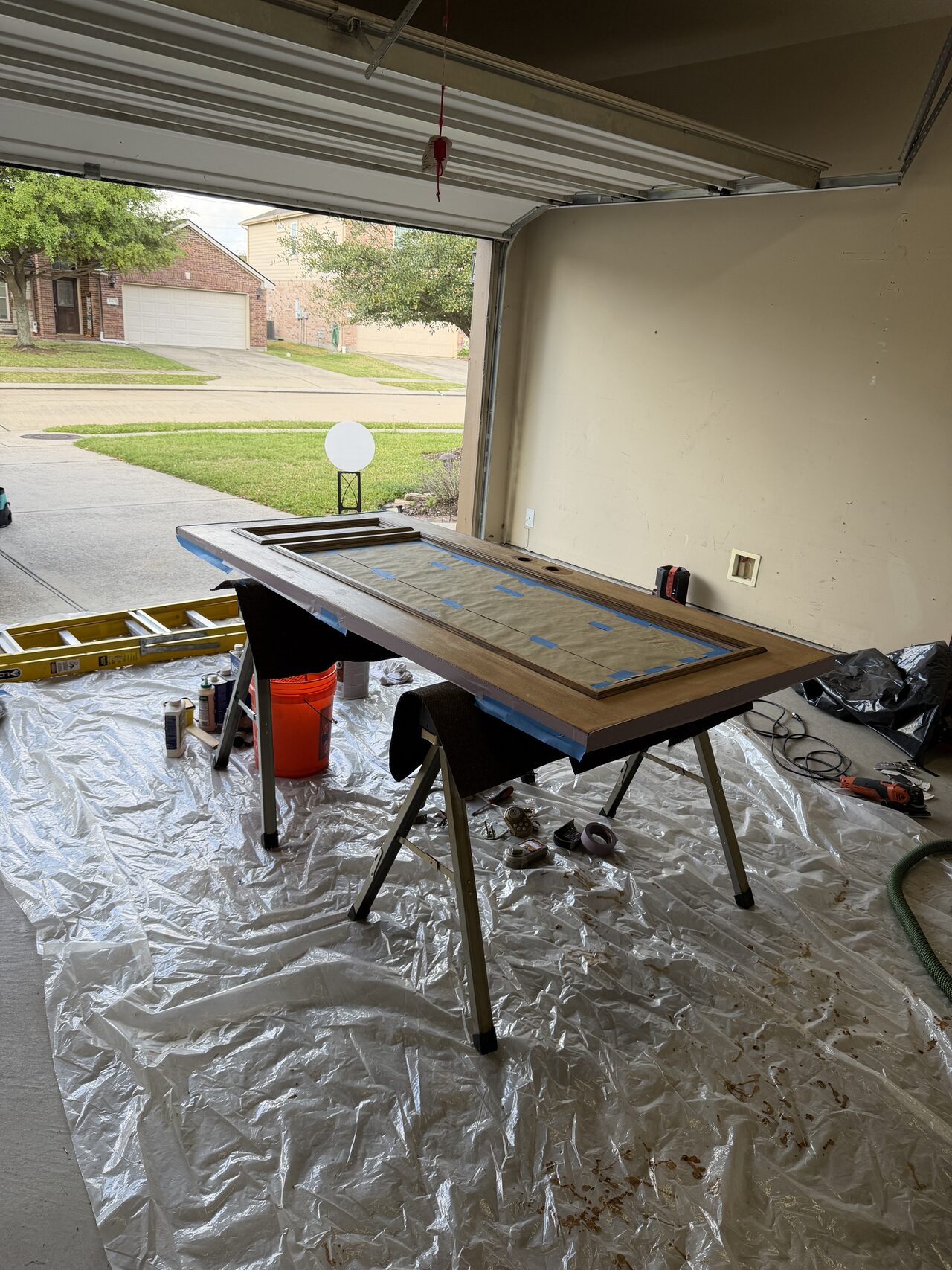 Entry door laid out flat on supports so panel faces and edges could be refinished evenly for a Joel Hodge project.