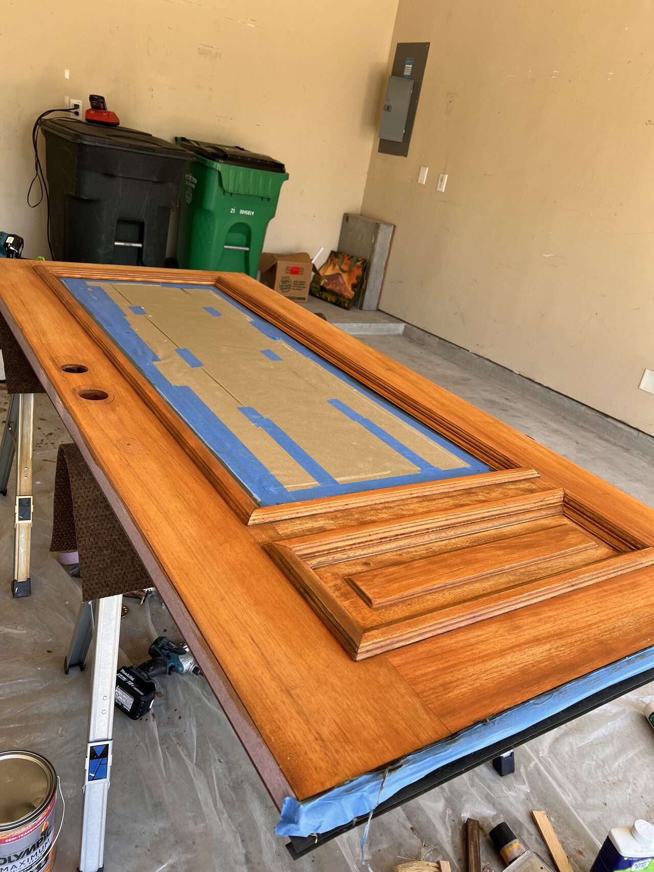 Stained entry door after finish work with taped glass and raised panels ready for hardware reassembly for a Joel Hodge project.