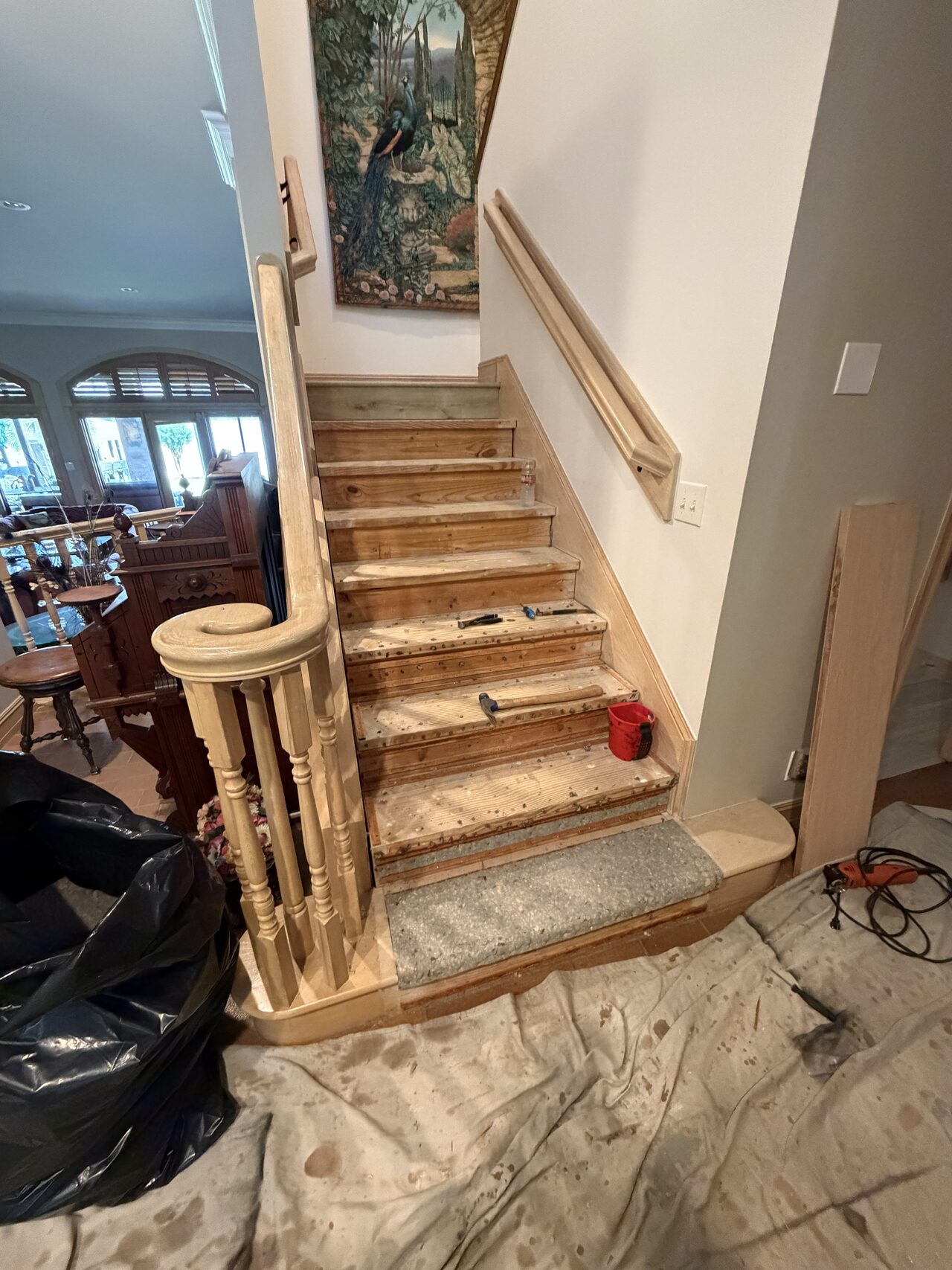 Main stair run in progress with treads exposed and finish materials staged nearby for a Joel Hodge project.