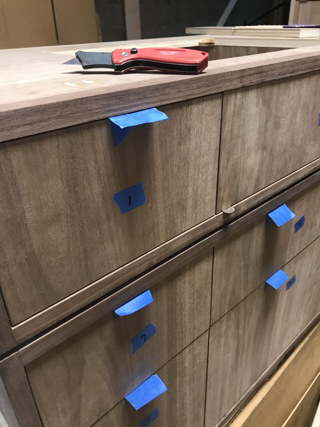 Close-up of taped drawer fronts showing reveal alignment and consistent horizontal spacing for a Joel Hodge project.
