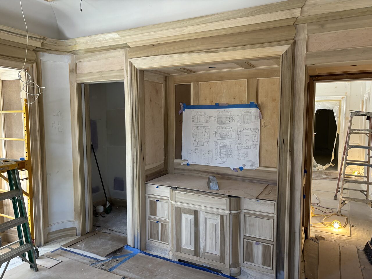 Built-in wall with base cabinets, panel framing, and ladder staged during finish installation for a Joel Hodge project.