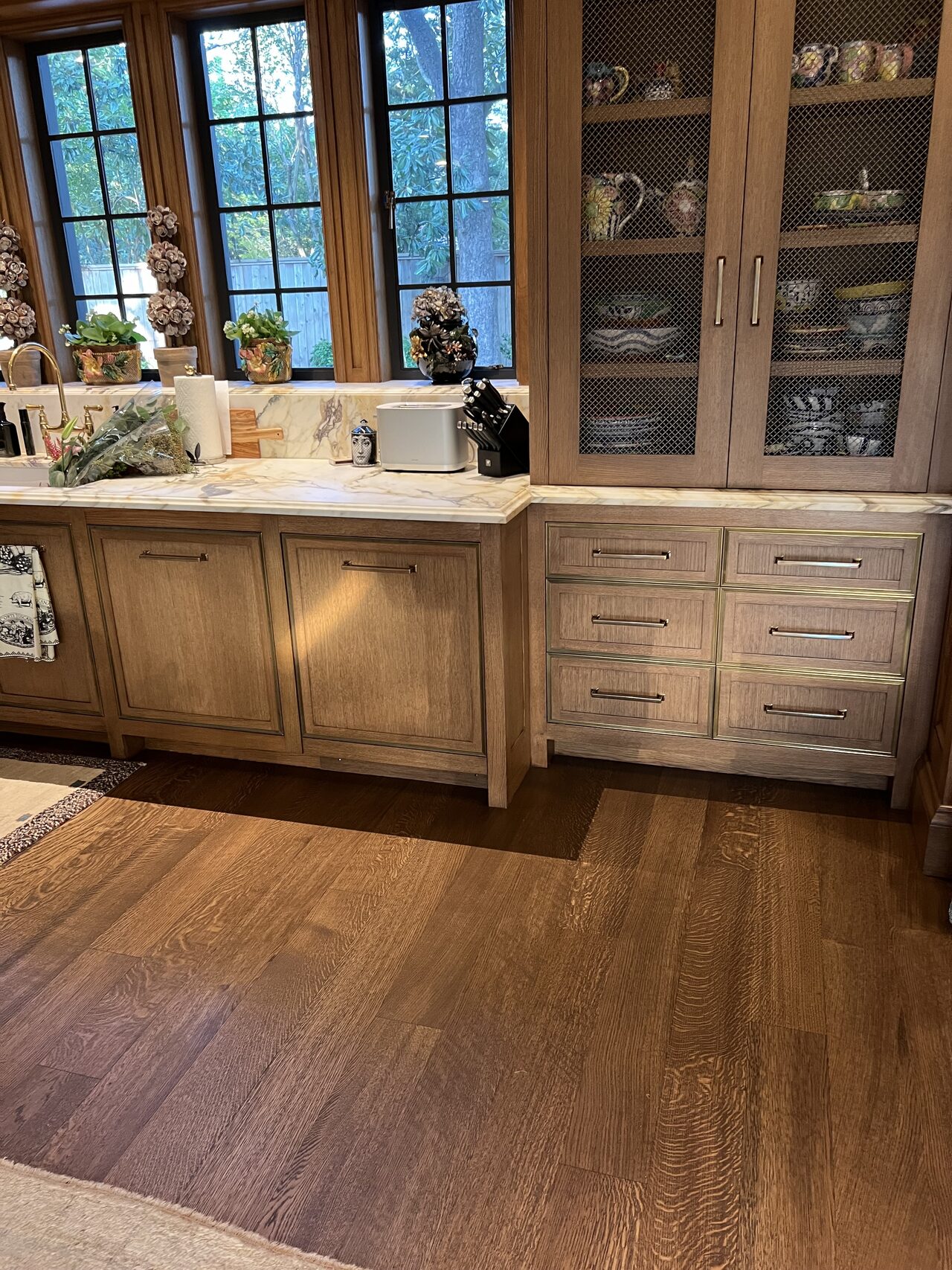 Finished wood cabinet run with glass doors, drawers, and counter area after installation for a Joel Hodge project.