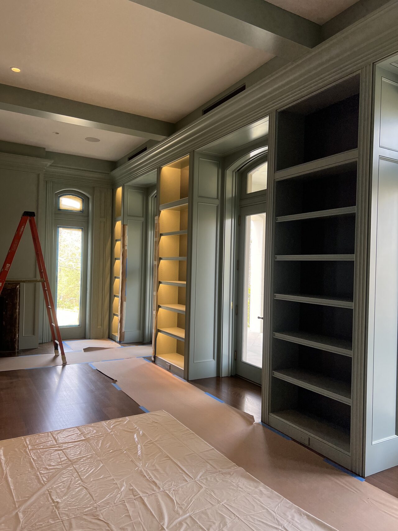Media wall shelves and tall side built-ins installed with floor protection still in place for a Joel Hodge project.