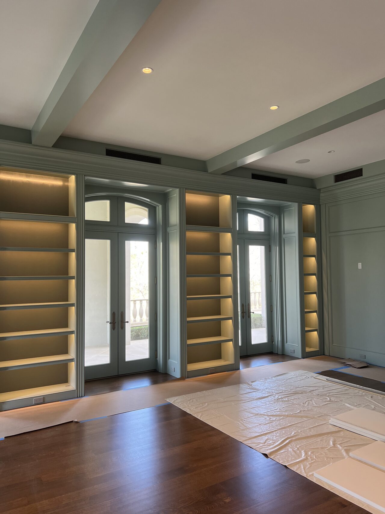 Side angle of the built-in media wall showing illuminated shelves beside the entry doors for a Joel Hodge project.
