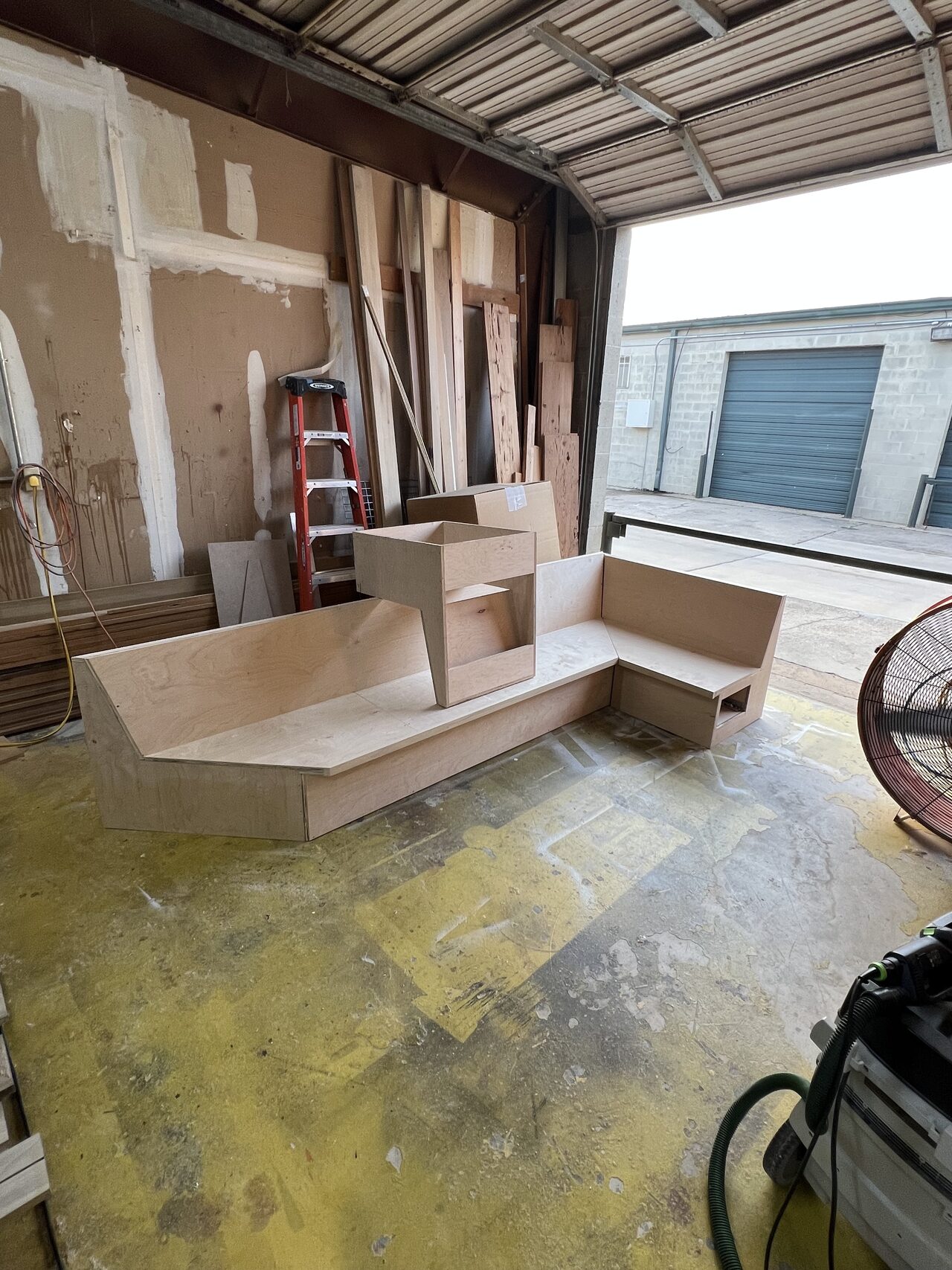Low base cabinet parts laid out on the shop floor to confirm storage layout and bench proportions for a Joel Hodge project.