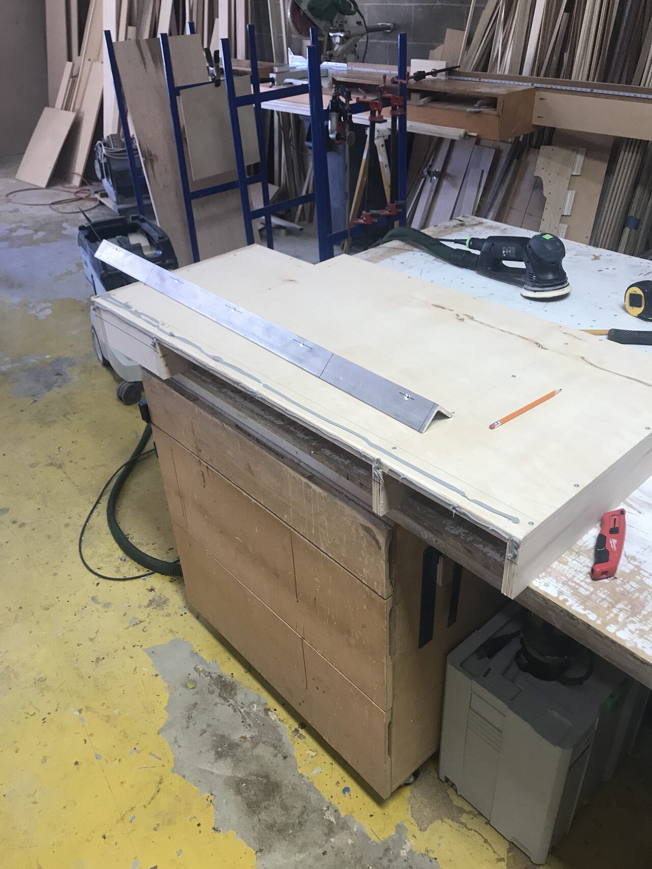 Base cabinet on the bench with straightedge and layout tools used for top and face alignment for a Joel Hodge project.