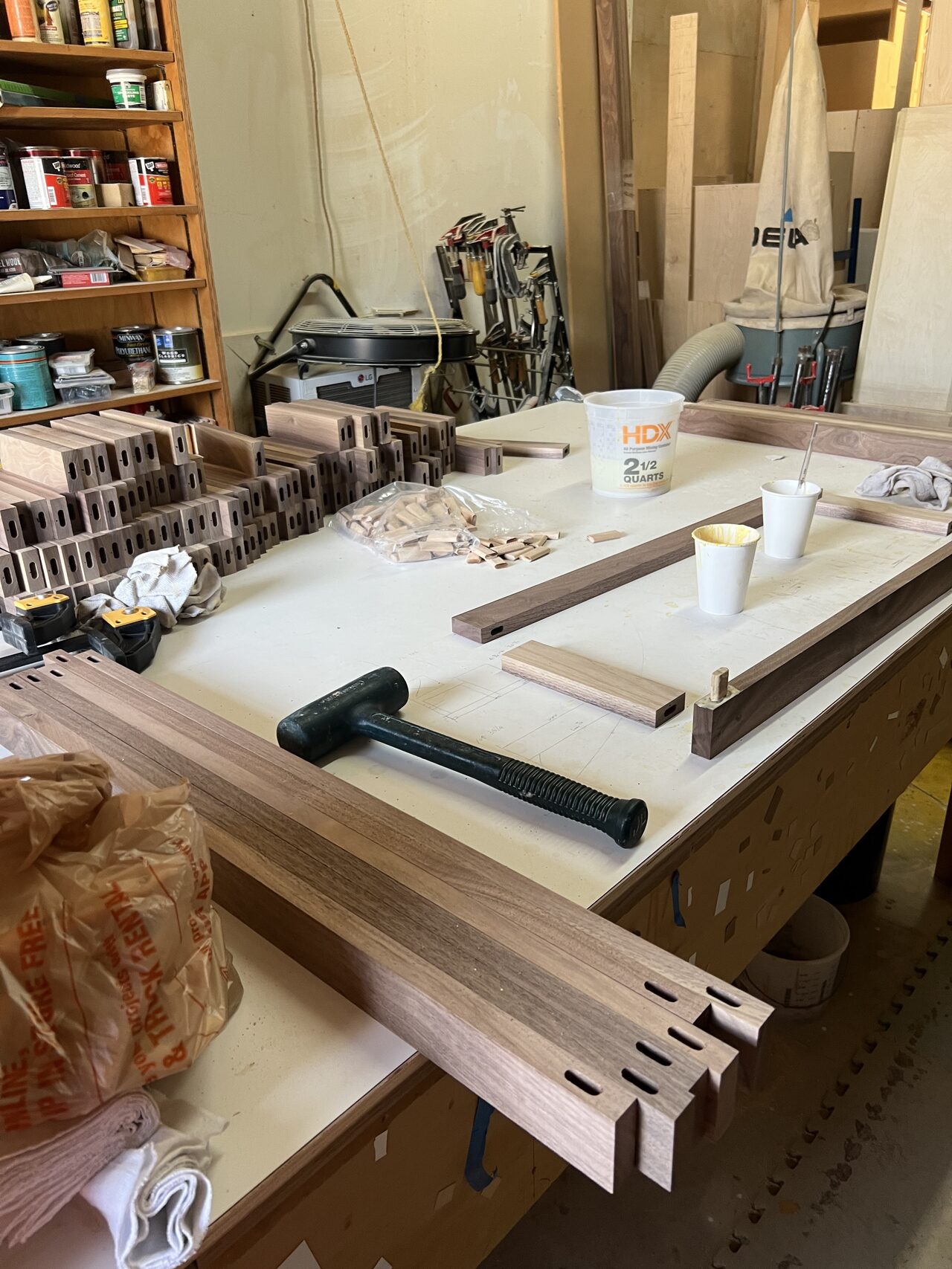 Long trim and rail pieces arranged on the bench for cutting and fitting for a Joel Hodge project.