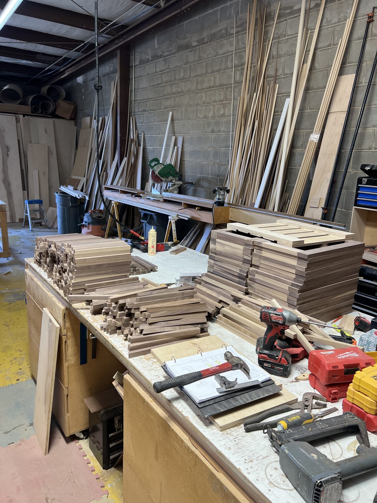 Bench full of cabinet parts and tools during detailed shop fabrication for a Joel Hodge project.