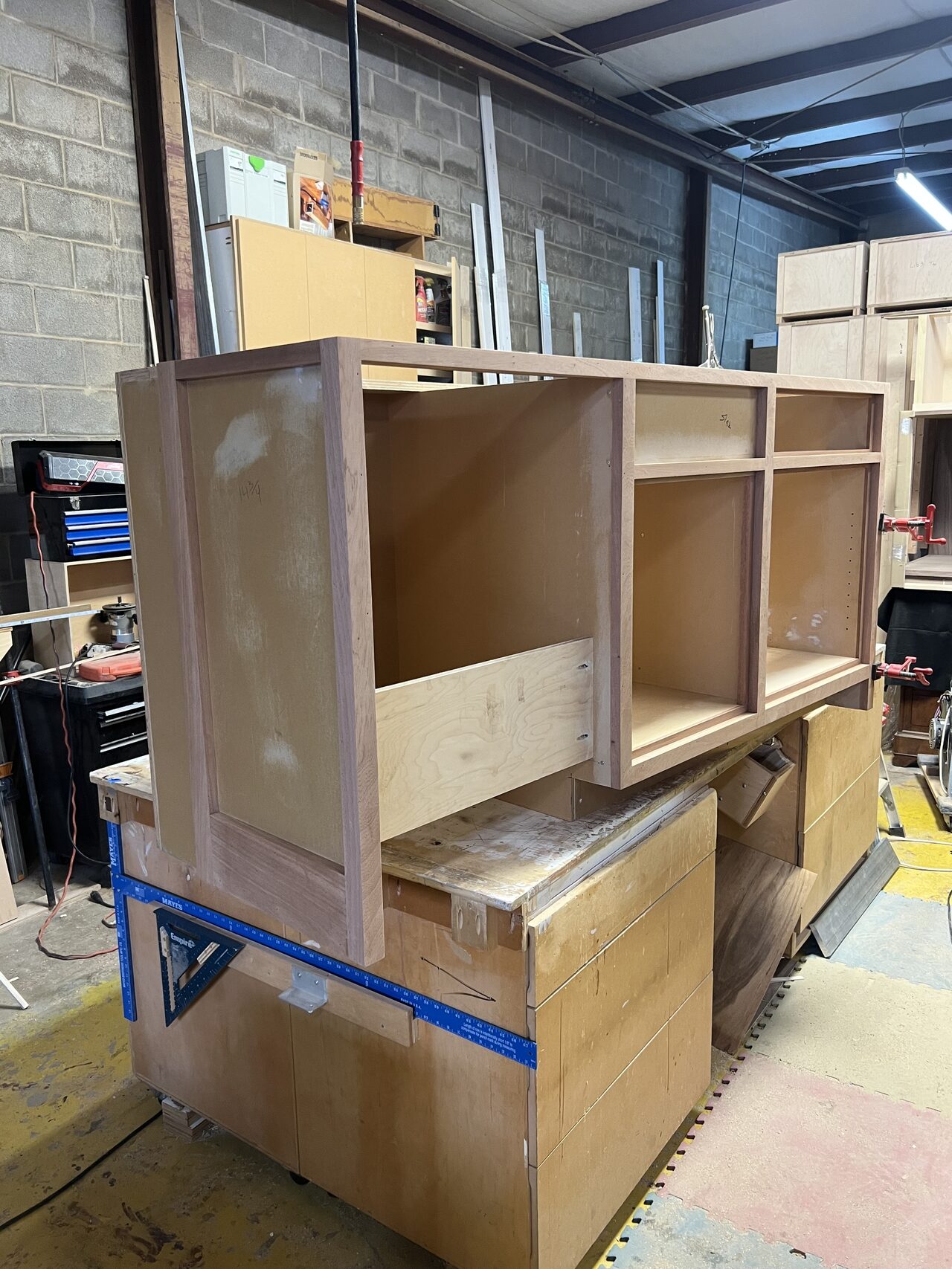 Tall shelving cabinet assembled upright with clamps and support blocks before finishing for a Joel Hodge project.