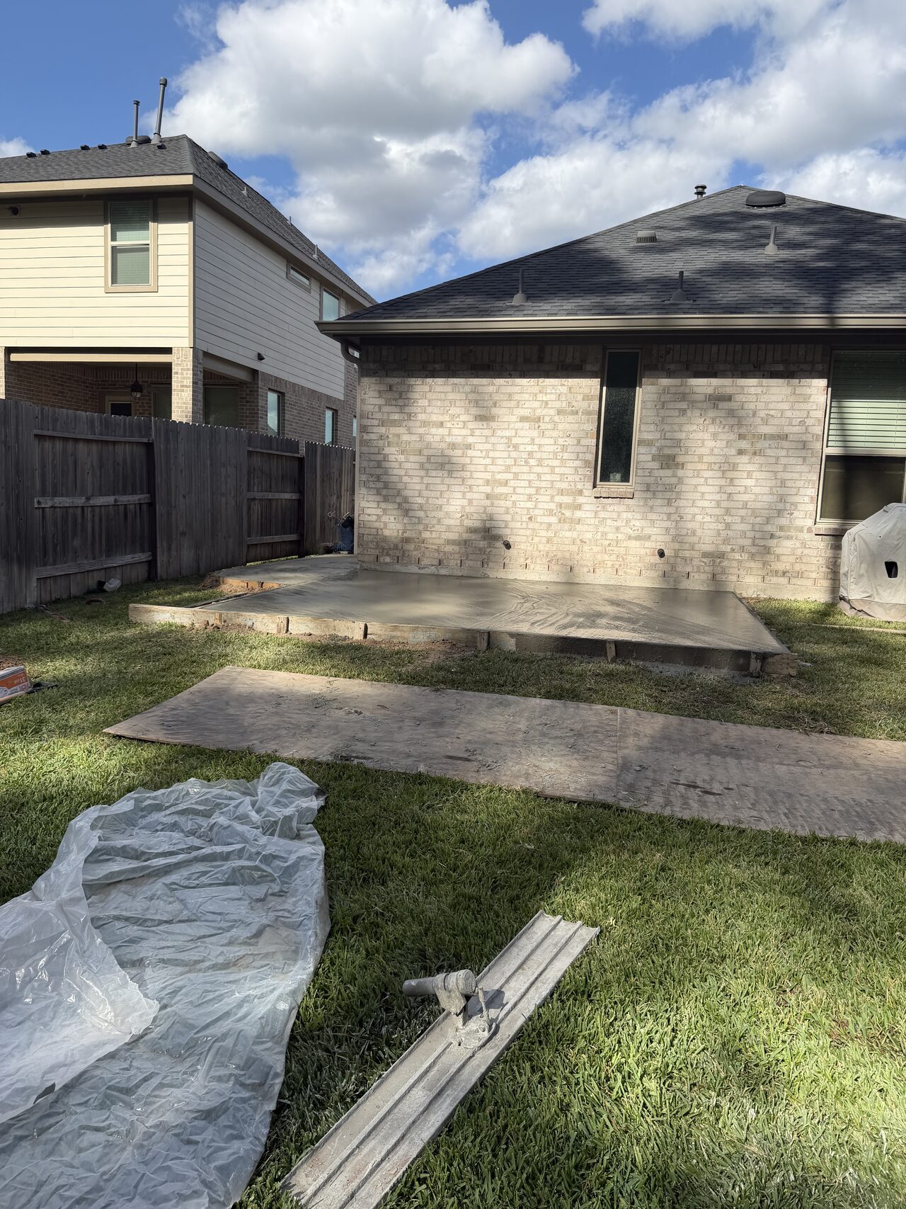 Rear yard view showing the concrete area layout before patio and side-path completion for a Joel Hodge project.