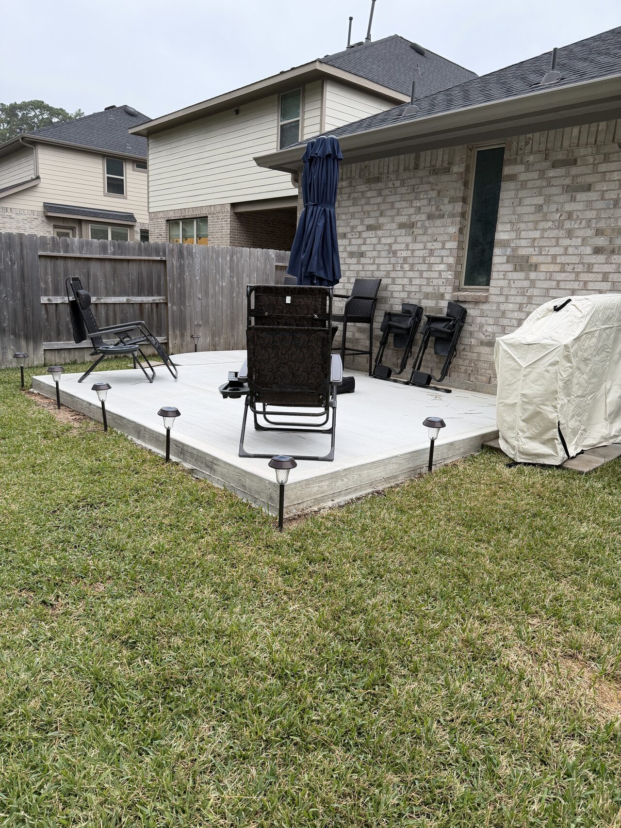 Completed backyard patio pad with outdoor seating set back in place after concrete work for a Joel Hodge project.