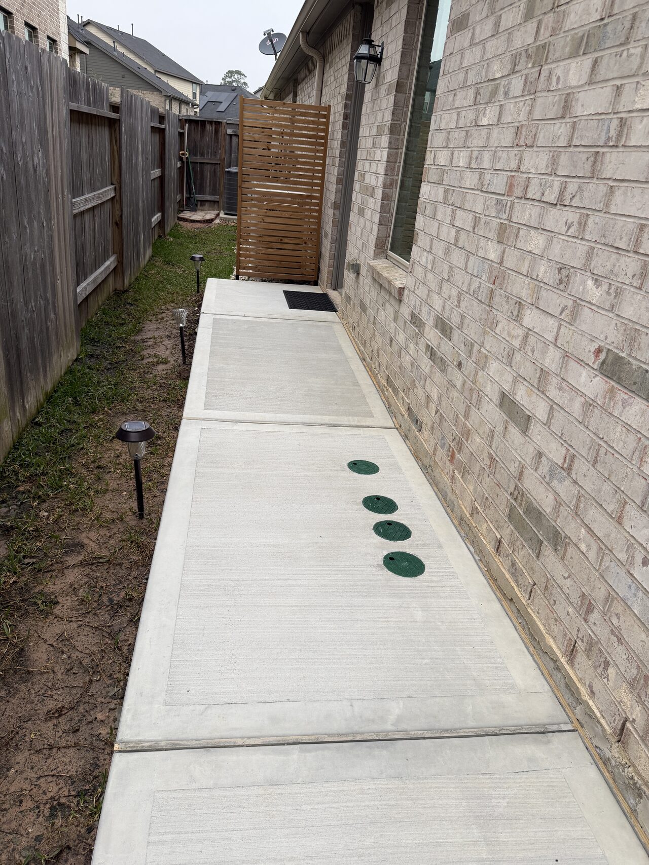 Finished side-yard concrete walkway with utility cleanouts coordinated through the slab for a Joel Hodge project.