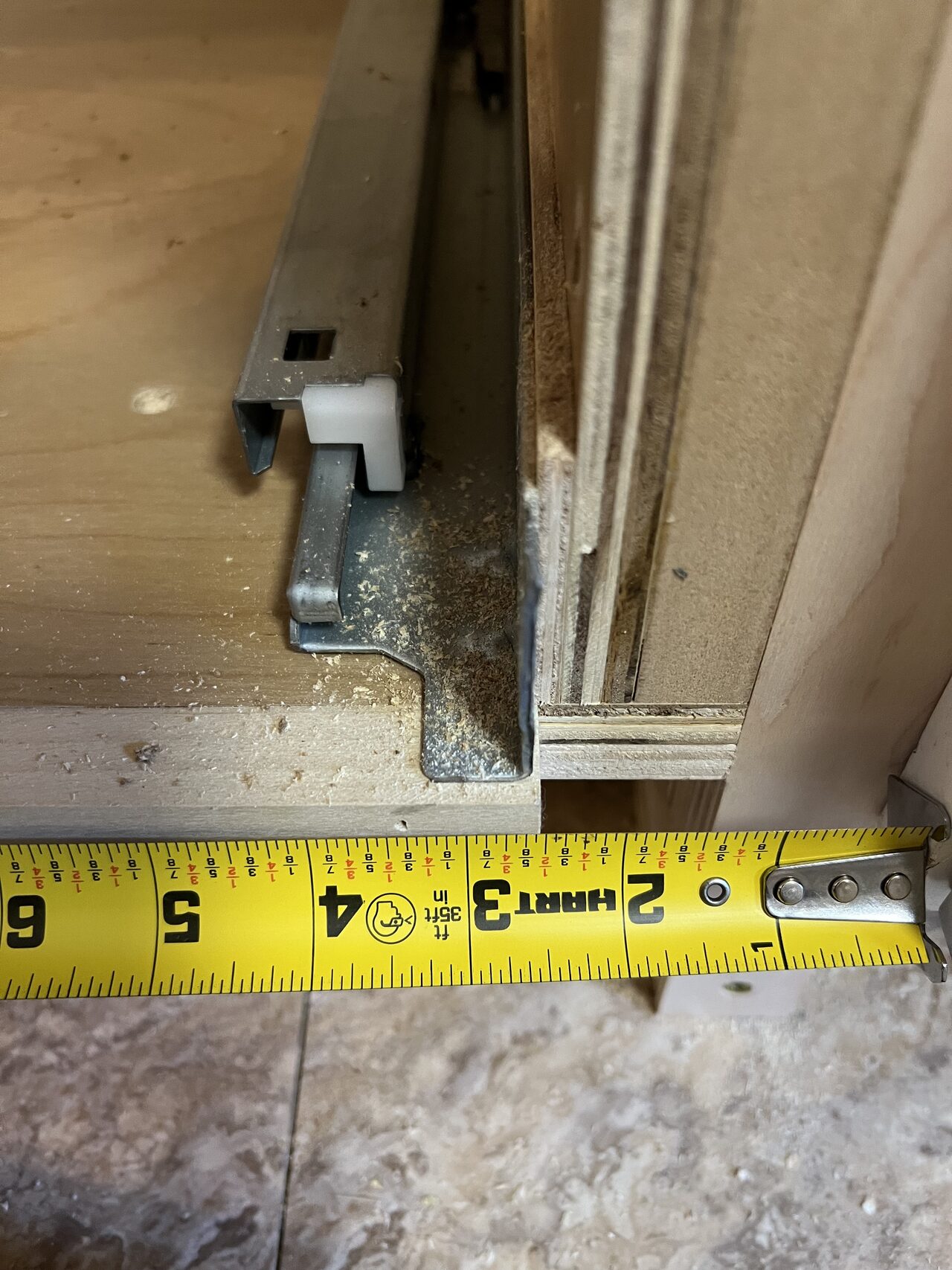 Tape measurement at cabinet and floor edge used to confirm fit against an existing wall condition for a Joel Hodge project.