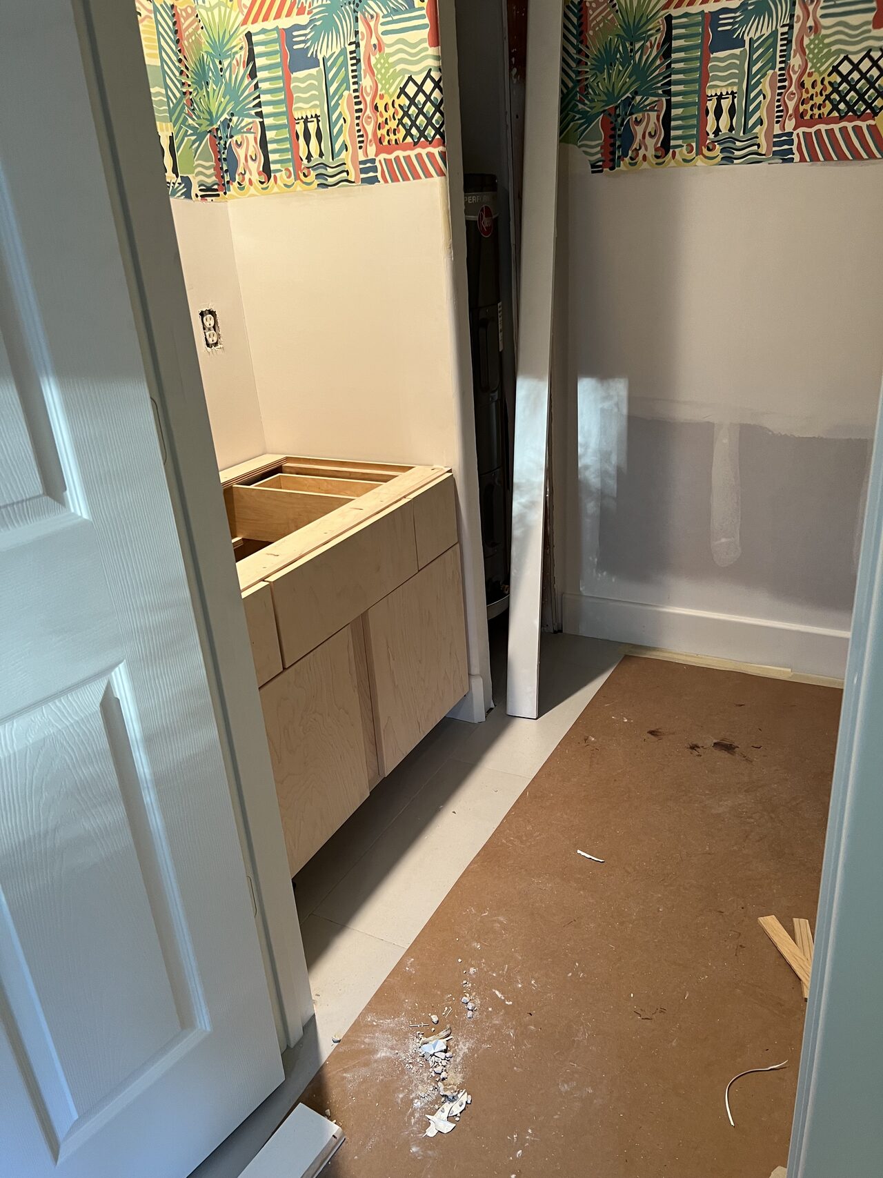 Small vanity cabinet set in the room with wall opening and floor protection visible for a Joel Hodge project.