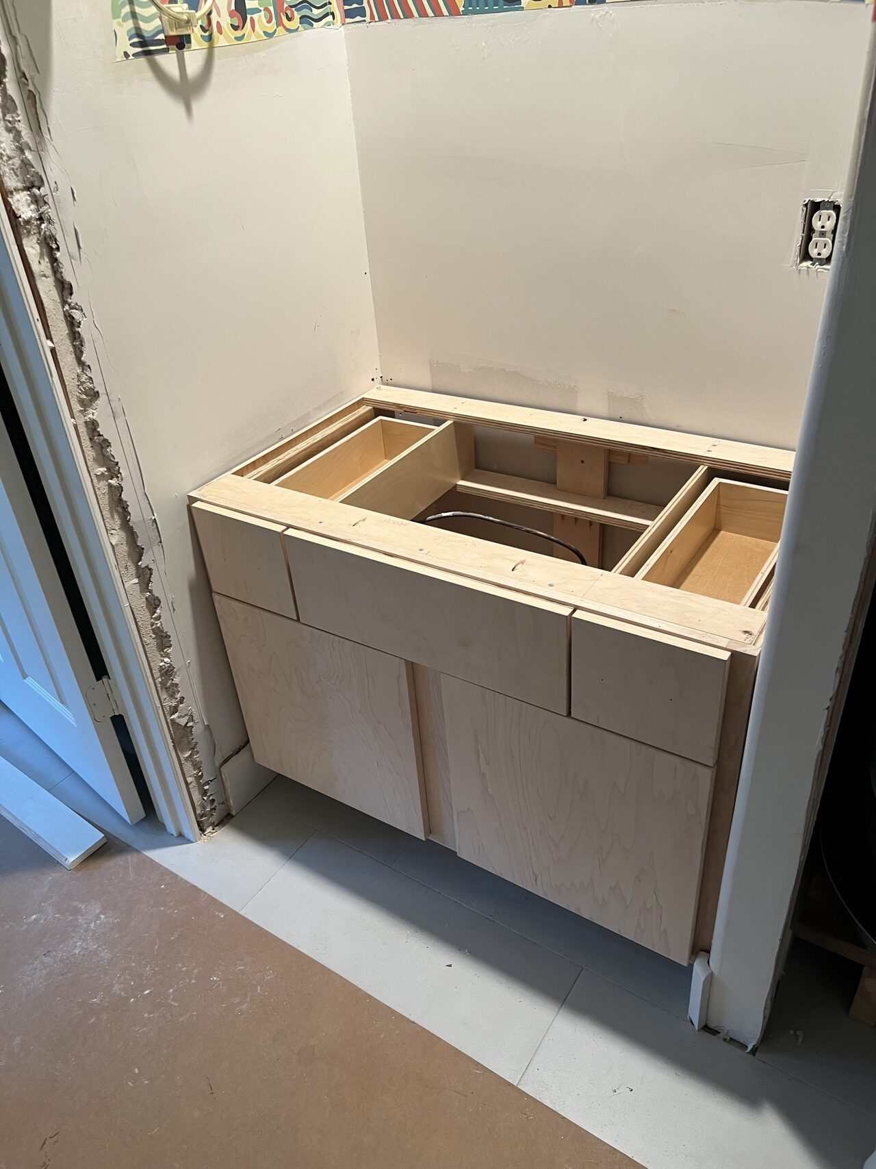 Unfinished vanity base installed in the alcove before countertop, sink, and final trim for a Joel Hodge project.